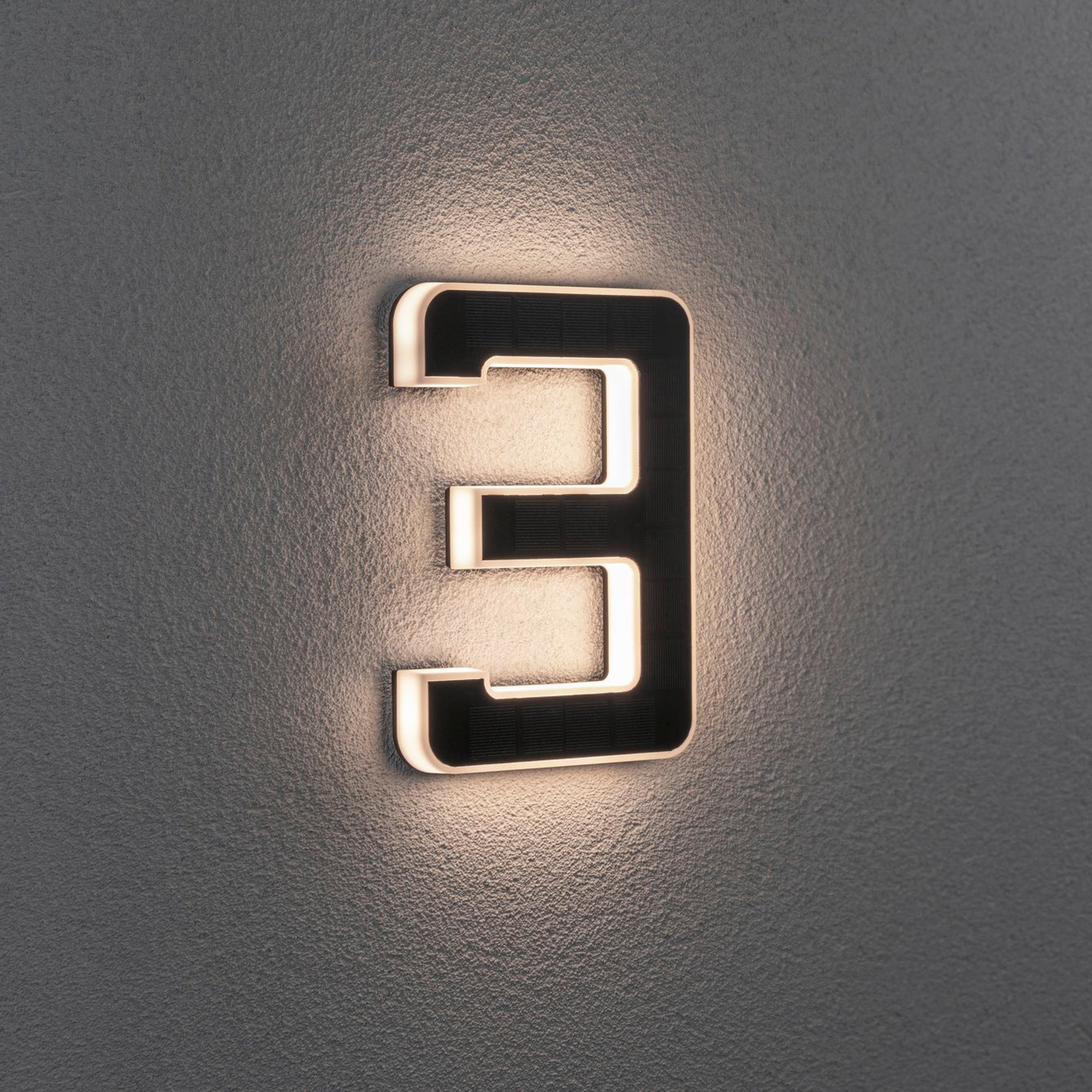 Illuminated number three on a textured wall, lit from behind.