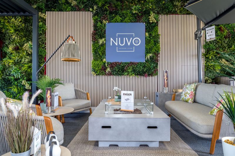 A modern, green-themed outdoor lounge with grey furniture, a vertical garden, and a NUVO sign in the background.