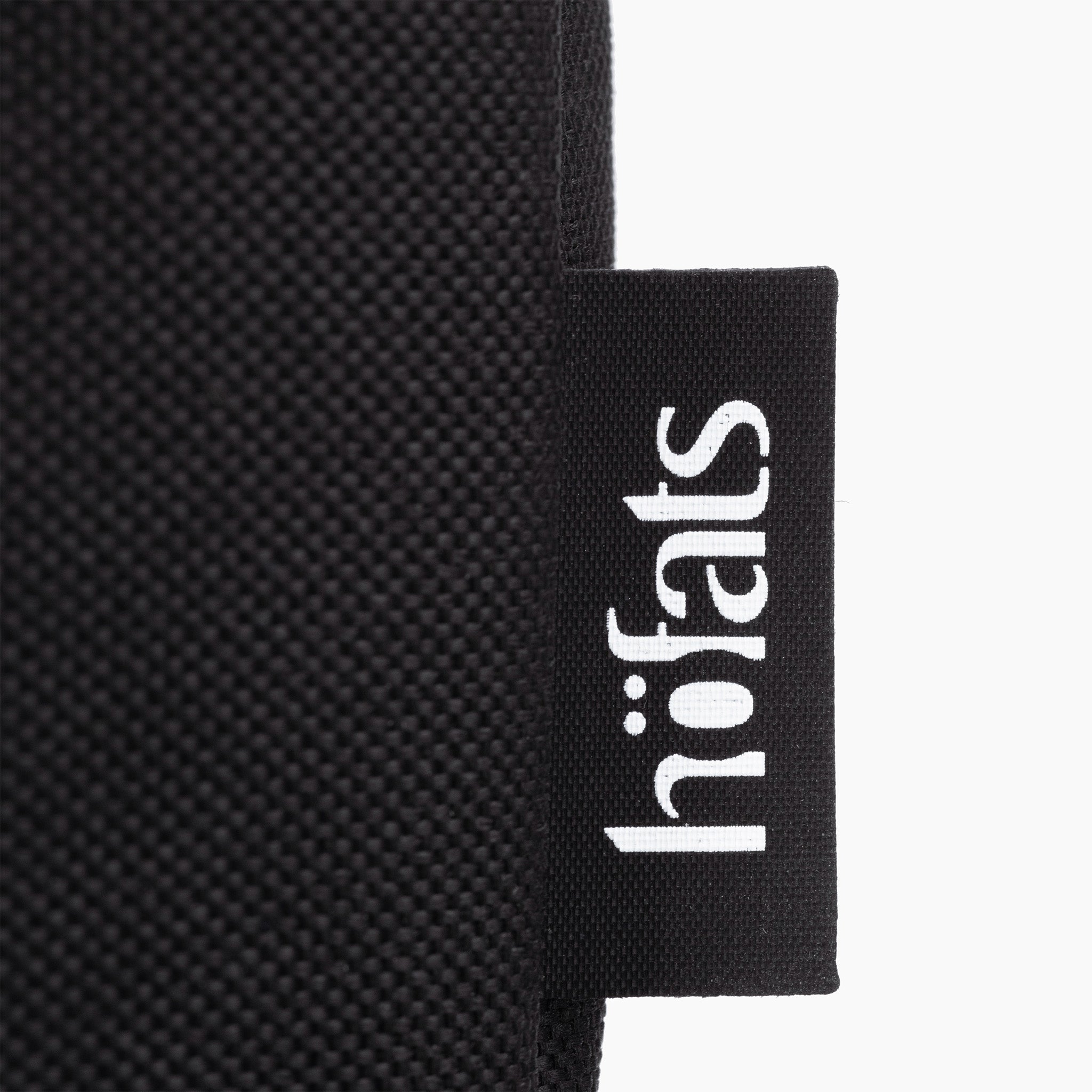 Close-up of a black tag featuring white "höfats" text, attached to the textured black, water-repellent material of the Höfats SPIN 1500 Cover.