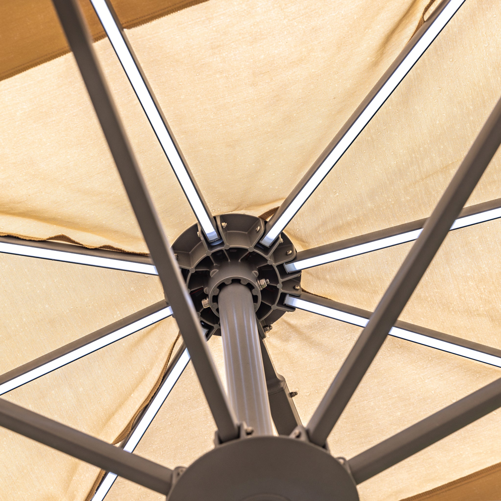 Close-up view of the underside of the Pallas 4m x 3m Rectangular Cantilever Parasol with LED Lighting in Beige, showcasing the spokes and central pole, perfect for providing garden shade.