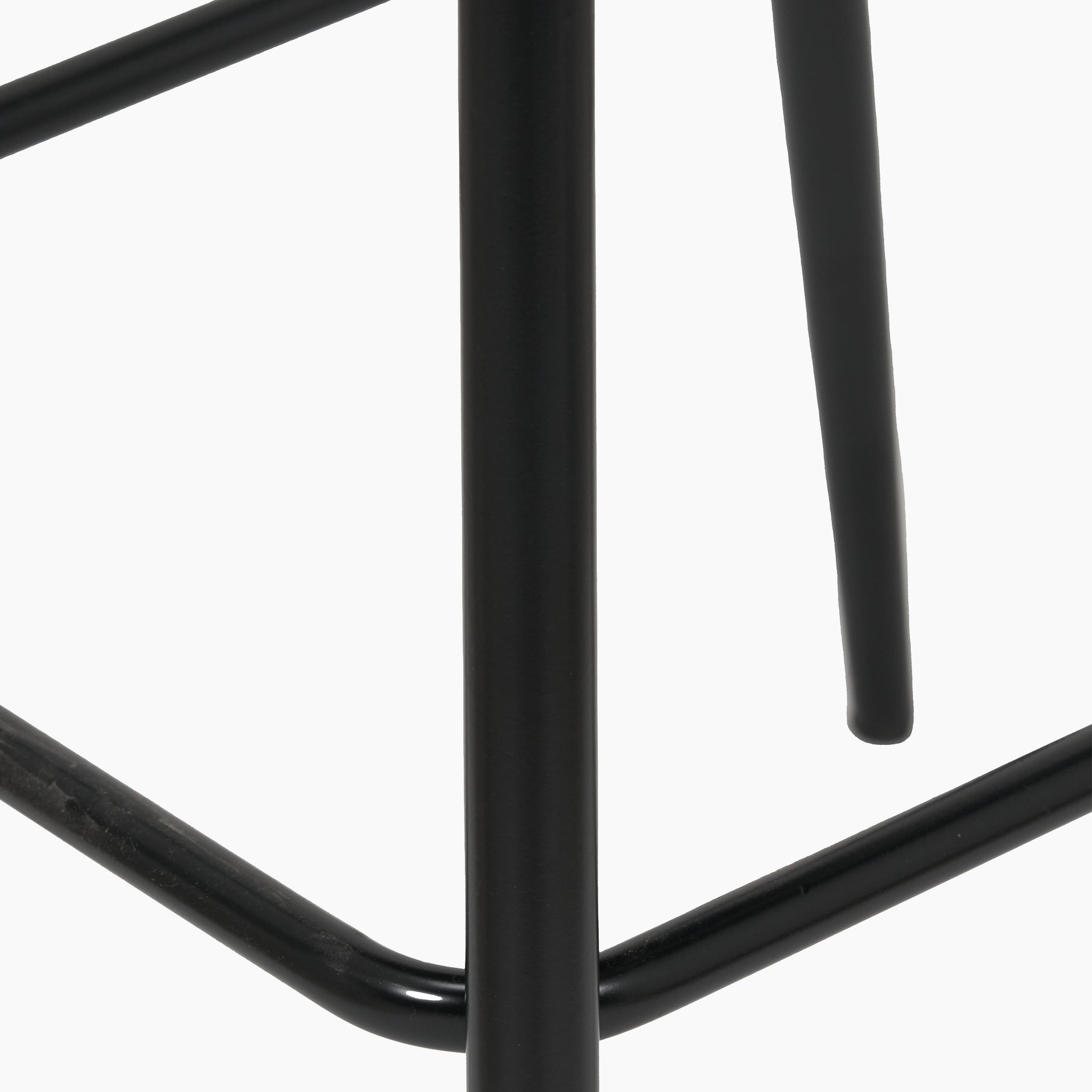 Close-up of the black metallic legs of the Turi Pebble Linen Mix and Black Metal Bar Stool, embodying a modern style with its minimalist design against a white background.