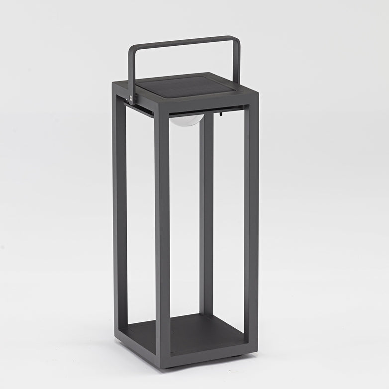 The Luxor Large Floor Outdoor and Indoor Solar Lantern in Charcoal is a modern, rectangular black metal lantern with clear sides, a handle on top, solar lighting, and an automatic switch.