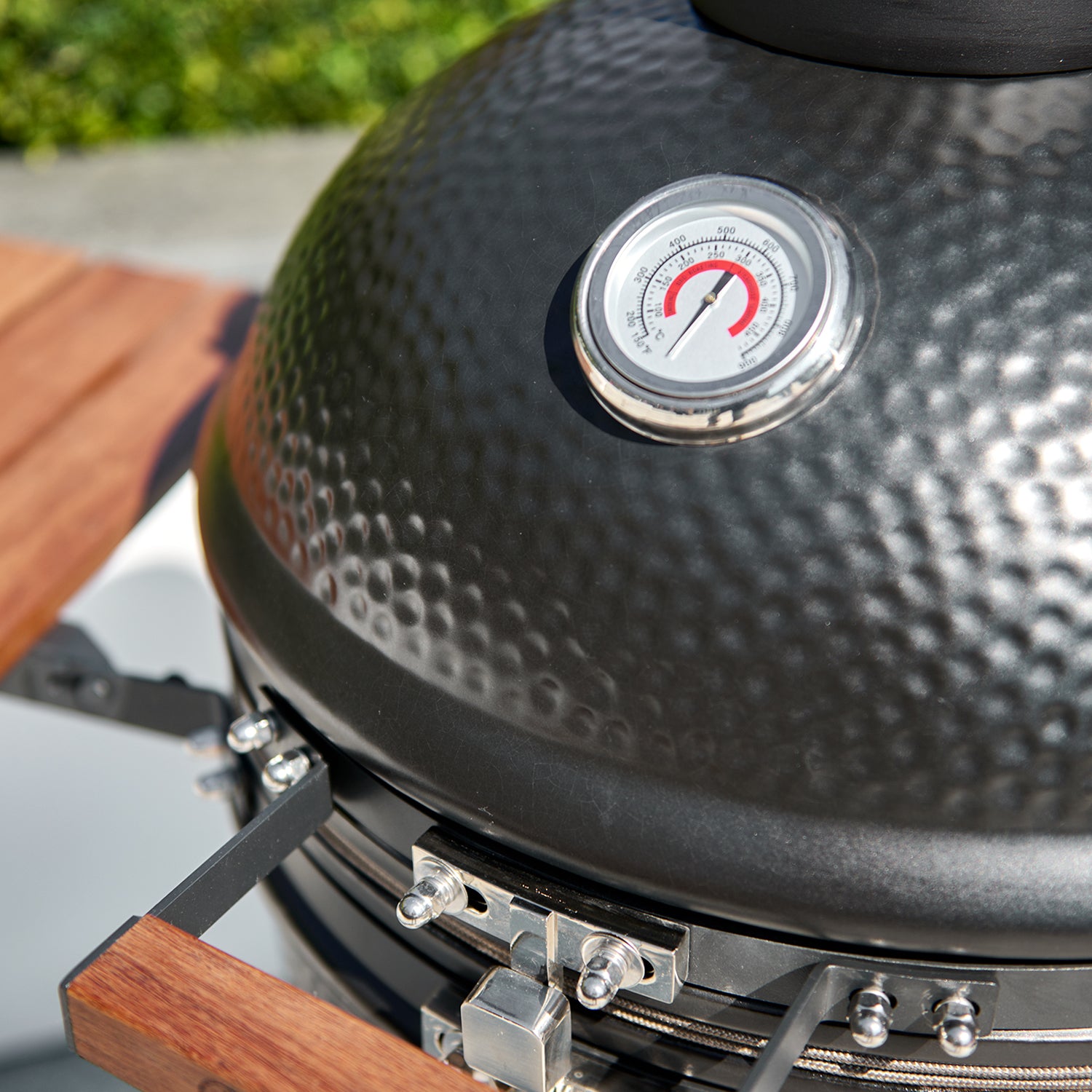 Close-up of the Kamado BBQ 22" Ceramic Grill in Black, featuring a round, black, textured design with a temperature gauge on the lid, set on a wooden surface.