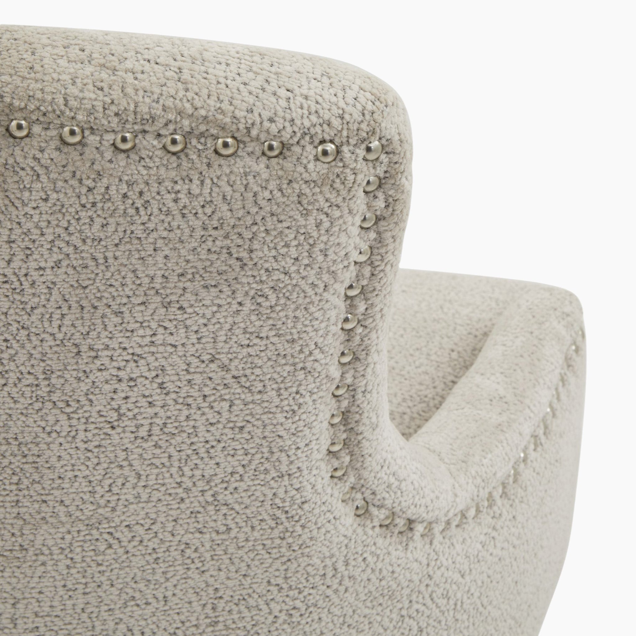 A close-up of the backrest on the Brockham Taupe Dining Chair showcases a beige textured finish and silver nailhead trim, enhanced by a resilient taupe woven fabric.