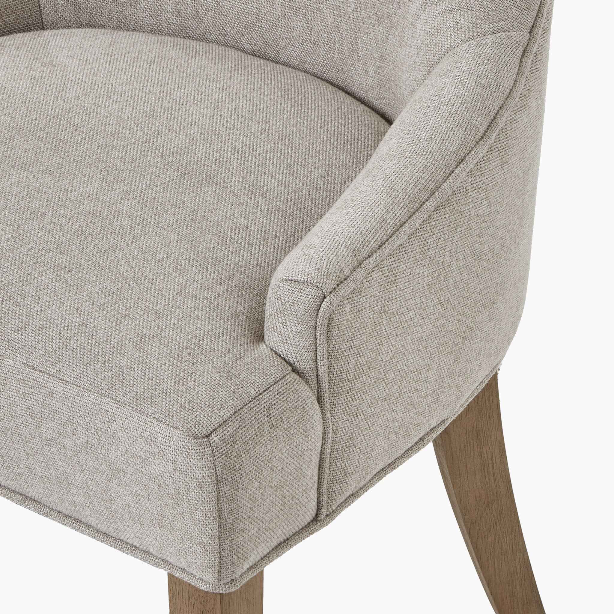 A close-up view of the Brockham Oatmeal Twill Dining Chair, featuring rubberwood legs and a curved armrest design.