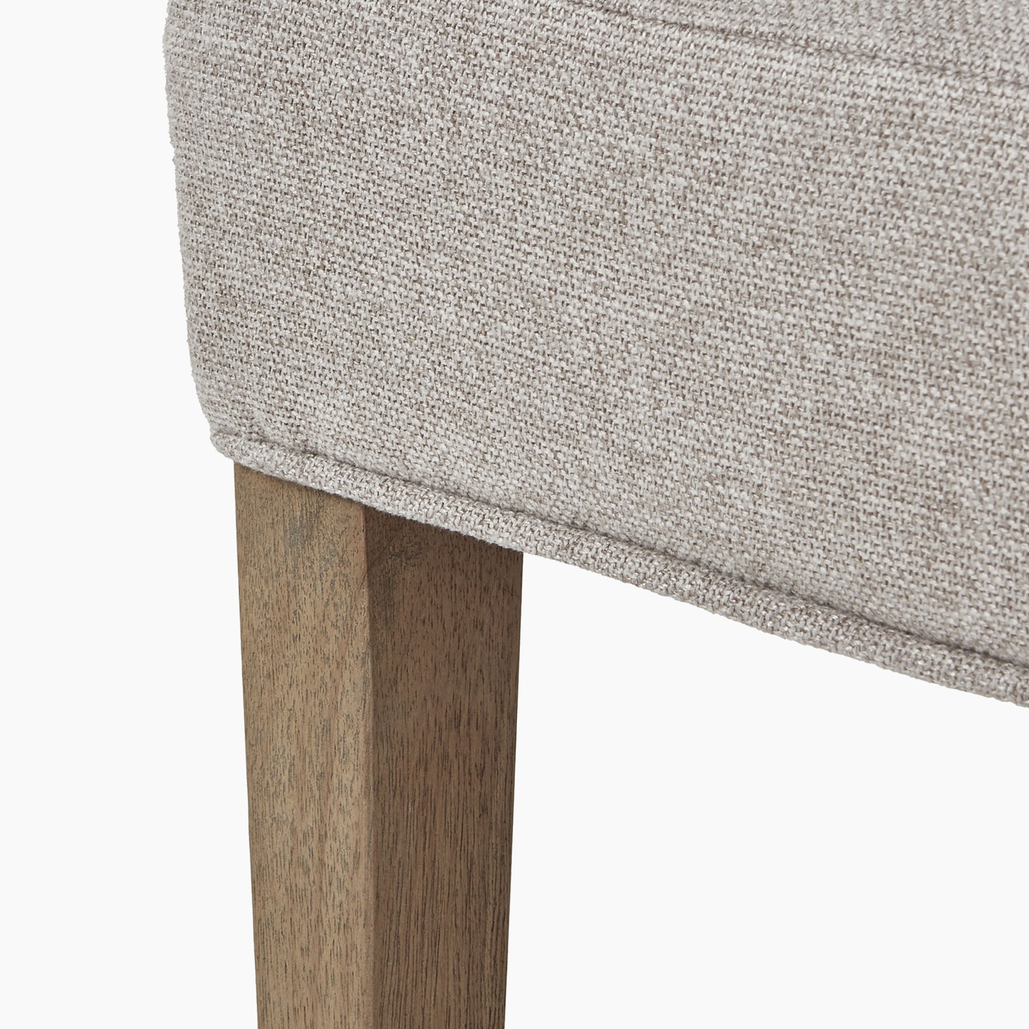 Close-up of the Brockham Oatmeal Twill Dining Chair, featuring a beige fabric cushion elegantly perched on its rubberwood legs, highlighting its oatmeal upholstery.