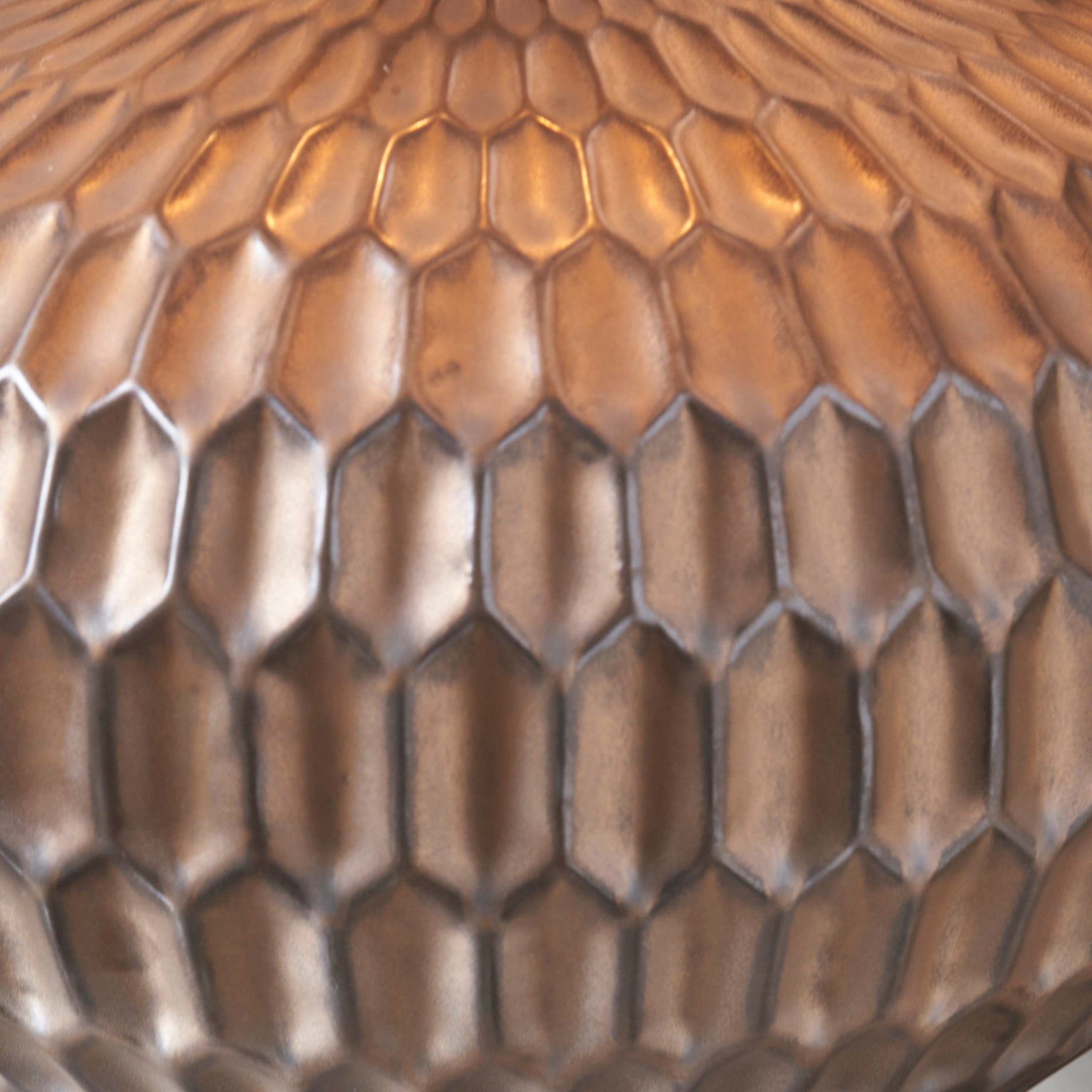 A detailed view of the Cassius Bronze Textured Glazed Ceramic Table Lamp shows its metallic honeycomb pattern, beautifully reflecting a warm, golden light and creating a captivating bronze tone effect.