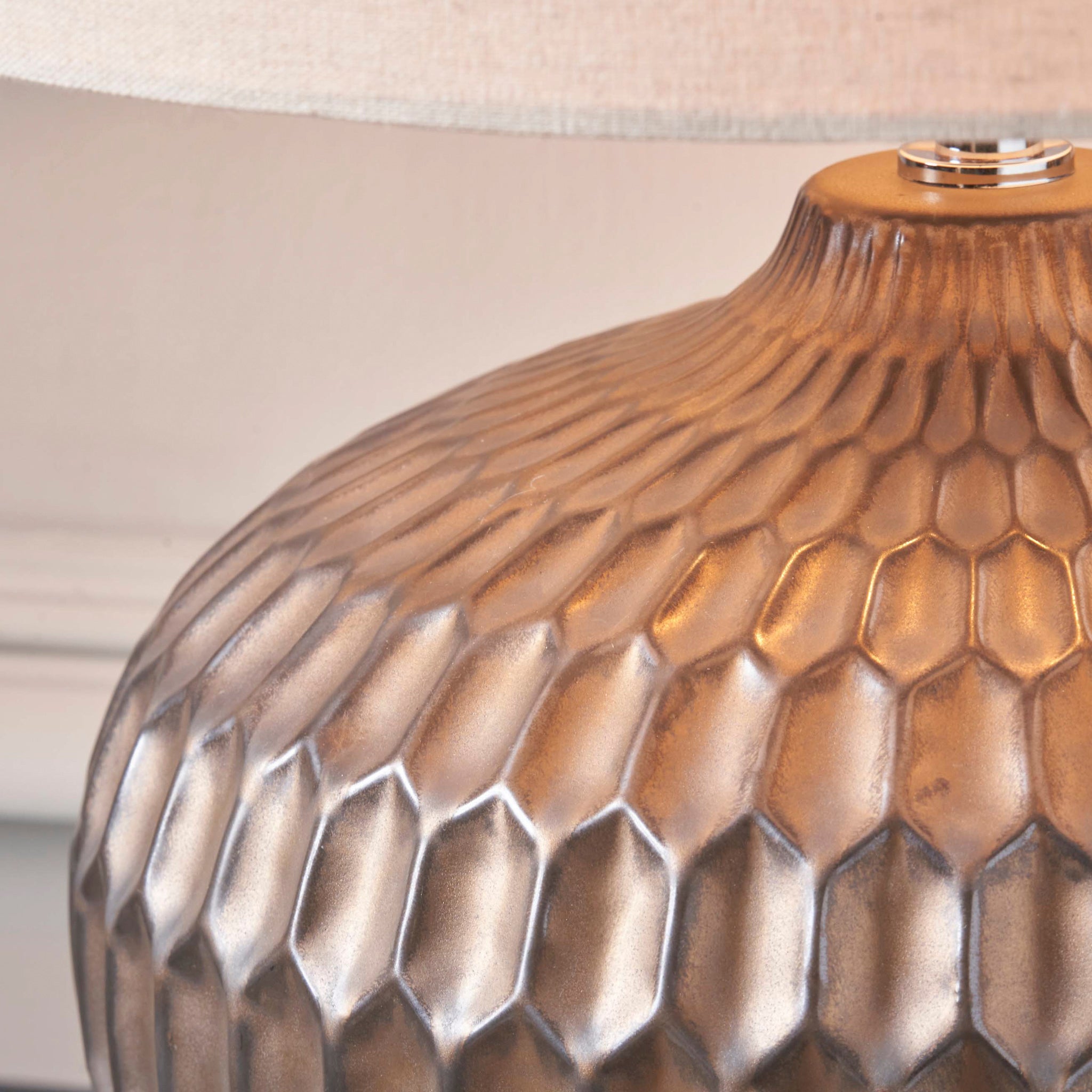 Close-up of the Cassius Bronze Textured Glazed Ceramic Table Lamp featuring a honeycomb pattern, complemented by a linen-look shade.