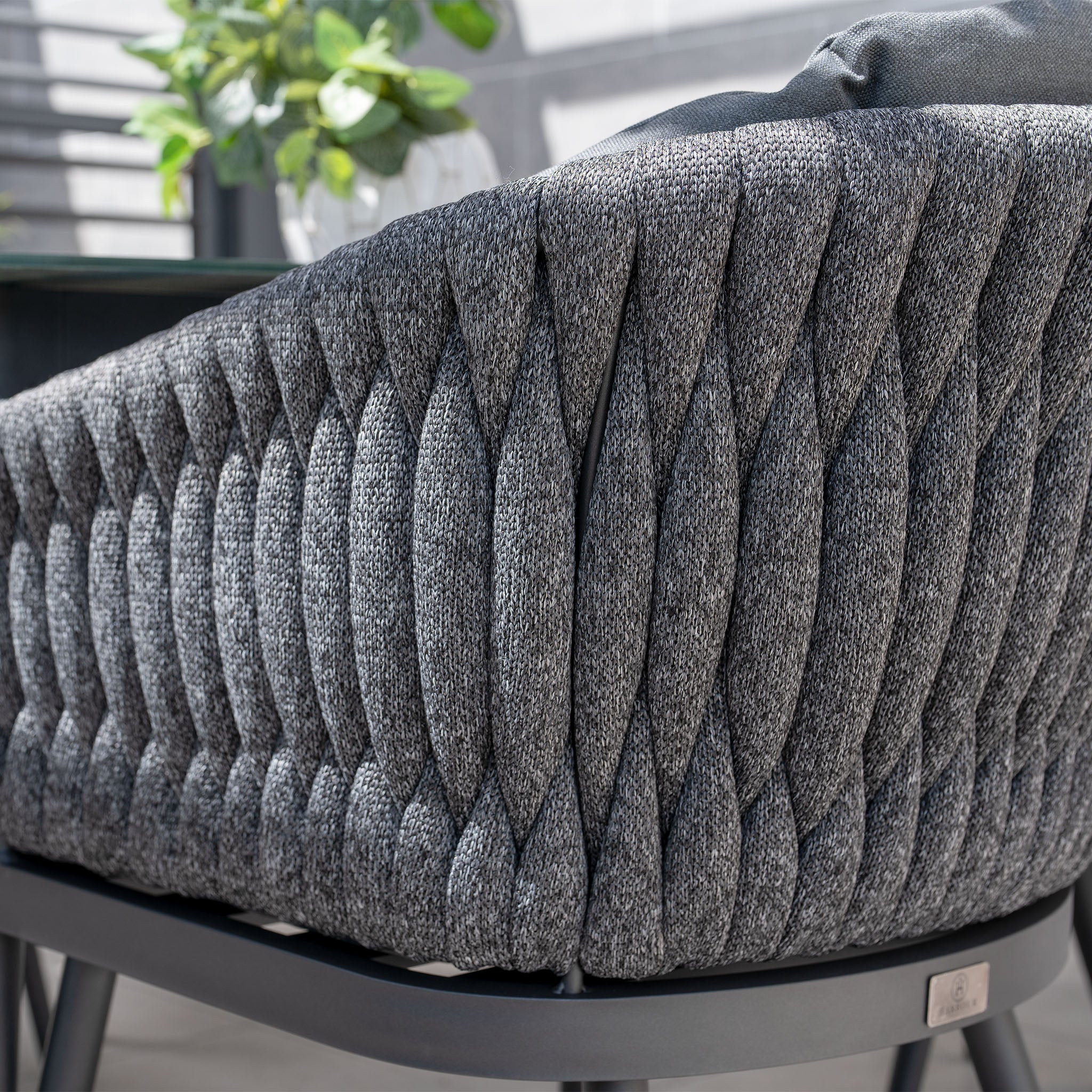 Close-up of the Palma 6 Seat Rope Oval Dining Set in Grey, featuring textured rope chairs with UV resistant cushions, complemented by leafy plants for a touch of nature.