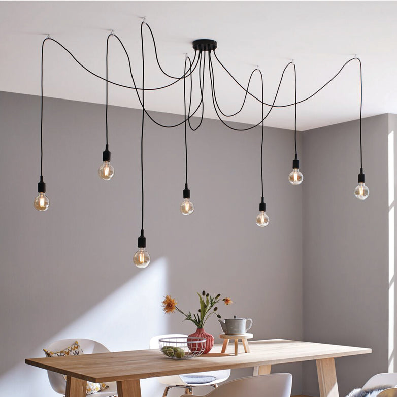 Featuring the Paulmann Filament LED Globe Bulb 2.7W E27 with elegant gold glass, this modern ceiling light fixture showcases energy-efficient LED technology with exposed bulbs and black cords, adding a touch of style above a minimalistic dining table.