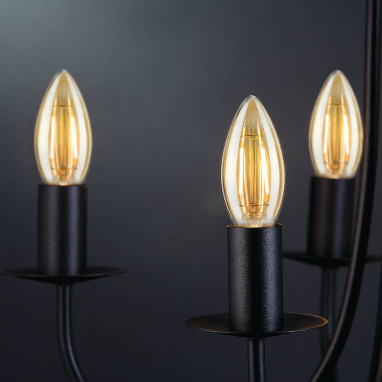 The Paulmann Filament LED Candle Bulbs, each at 2W and E14 base, elegantly illuminate a black chandelier with vintage charm against a dark background while benefiting from energy-efficient LED technology.