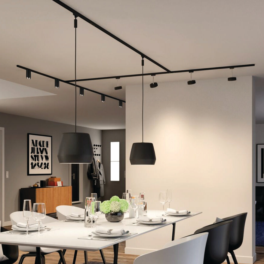 The modern dining room showcases a white table and black pendant lights, complemented by wall artwork and minimalist decor. The lighting uses the Paulmann Standard Reflector Bulb 7W GU10 in warm white for energy efficiency, offering optimal illumination that combines style with comfort.