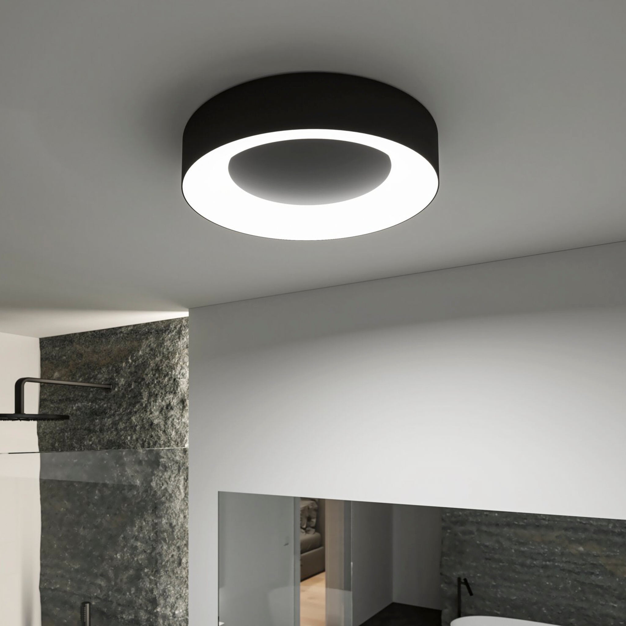 The Casca 25W LED Switch 2100lm Ceiling Light in Black Matt features a modern circular design that illuminates a contemporary bathroom, enhancing the sleek shower area and minimalistic aesthetics. Its adjustable light color allows for tailored ambiance, perfectly complementing the space.