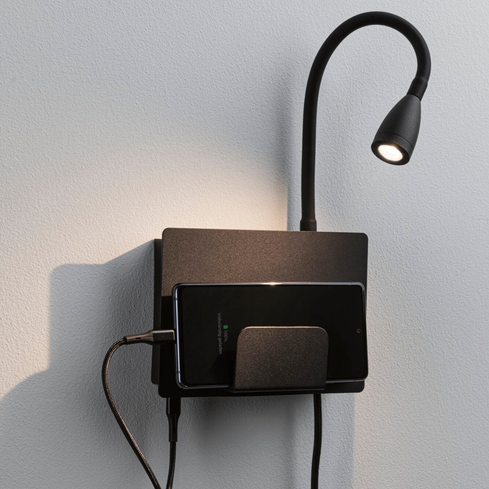 The Halina 3.5W LED Wall Light with USB Charging Port in Black Matt features a phone holder with a USB Type-C charging socket, paired with a flexible arm for optimal lighting.