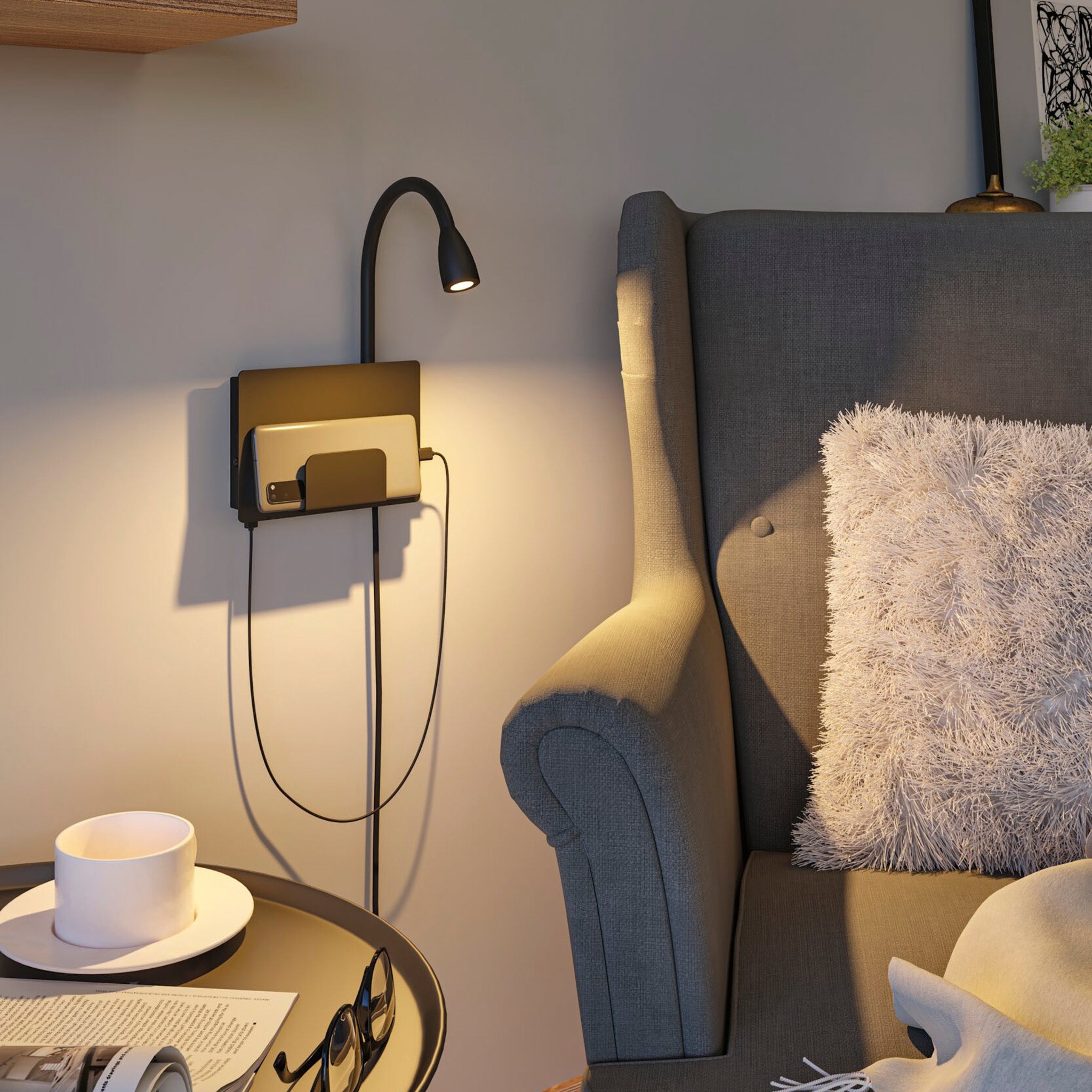 Cozy reading nook with a grey armchair, the black matt Halina 3.5W LED Wall Light featuring a flexible luminaire arm, round table, and a fluffy pillow. Plus, there's a USB Type-C charging socket for added convenience.