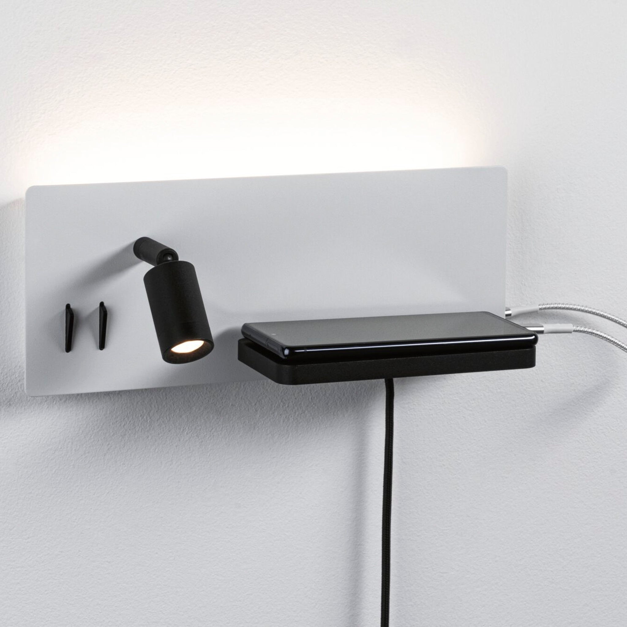 The Paulmann Serra 5.5W/2.6W LED Right Hand Wall Light in white and black offers a modern design with a wall-mounted luminaire that includes a black spotlight, hooks, and a convenient shelf for placing your phone. This stylish package is equipped with a USB Type-C port for easy charging, providing both flexible lighting and functionality with its 3-step dimming feature.