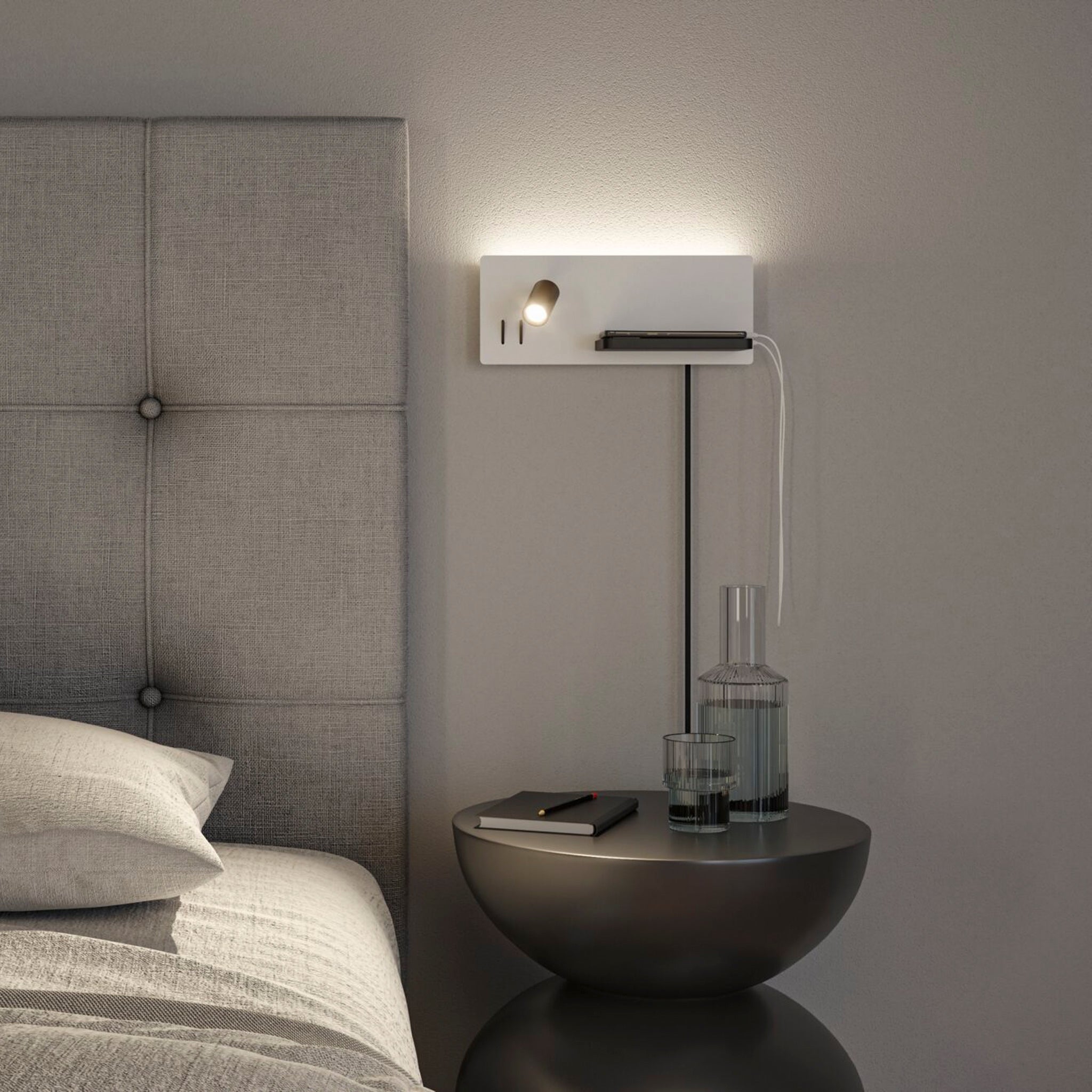 A minimalist bedroom showcasing a gray headboard, the flexible Paulmann Serra LED wall-mounted reading light with a 3-step dimmer and USB Type-C port, alongside a sleek bedside table adorned with a book, glasses, and water for added convenience in this modern setting.