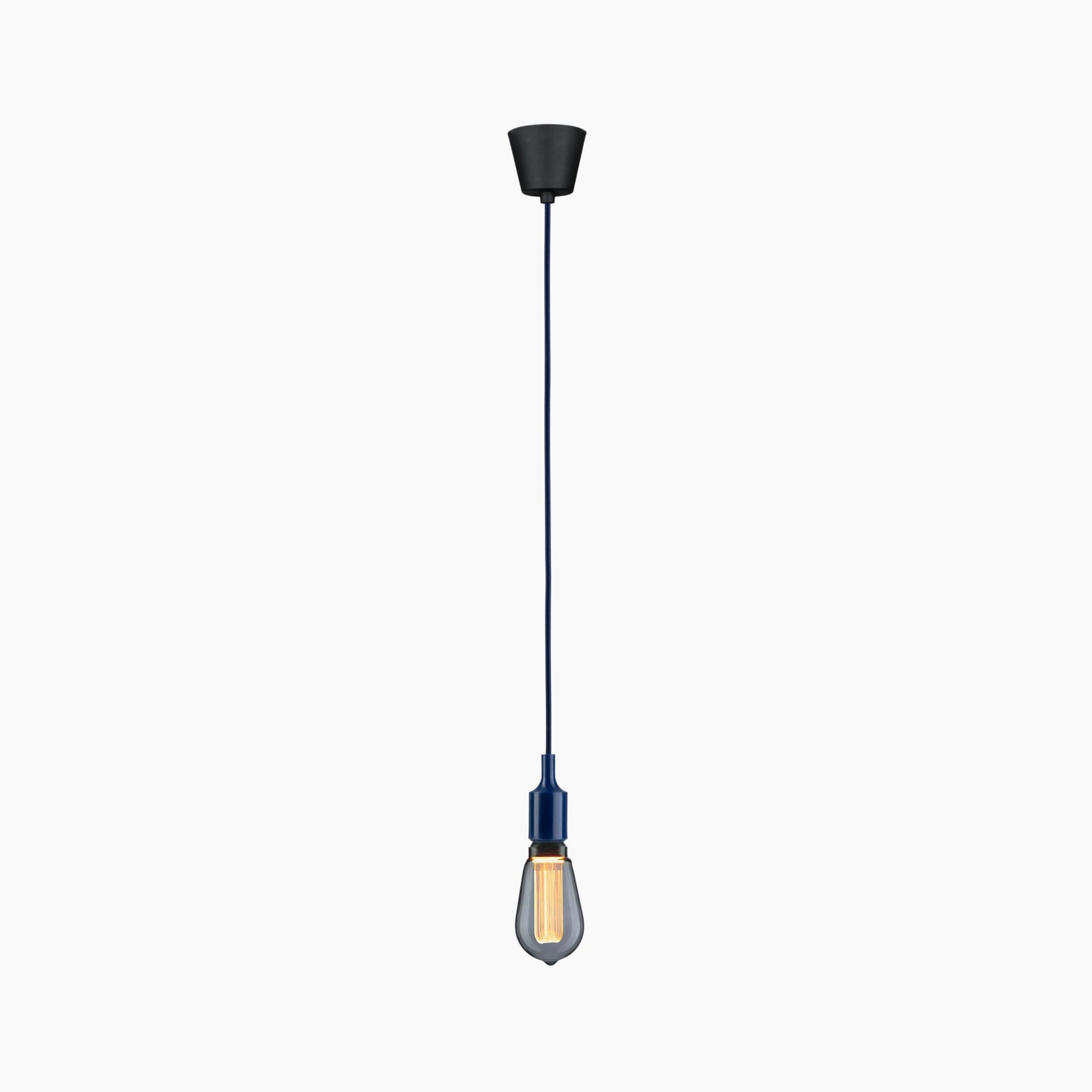 The Paulmann - Neordic Ketil 60W Dimmable Pendant Light in Night Blue showcases a minimalist design, complemented by a sleek black cord and a vintage-style exposed bulb against a white backdrop. Its silicone accents in night blue offer a subtle touch of elegance.