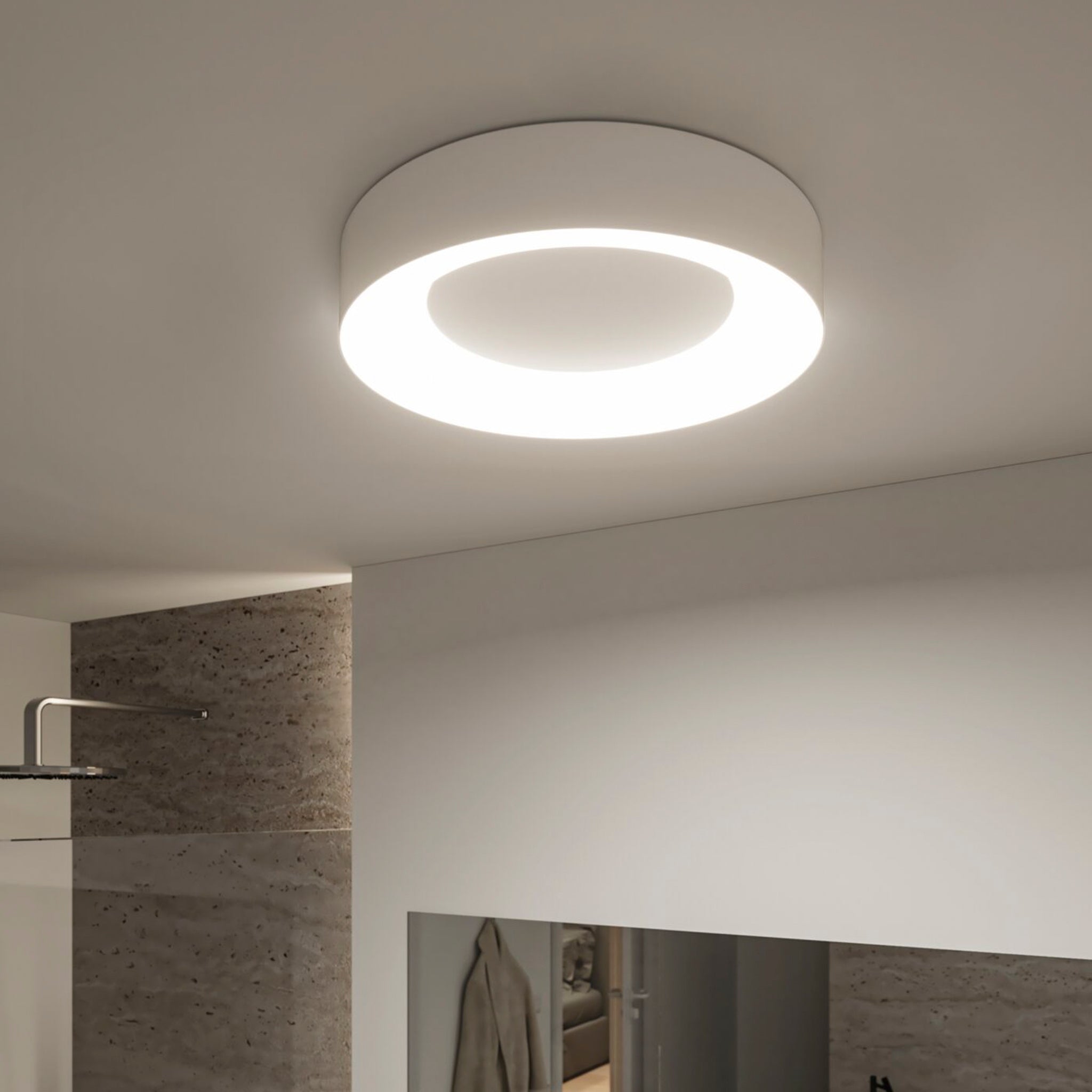 The Casca 25W LED Switch 2100lm Ceiling Light in White illuminates a minimalist room with sleek, neutral-toned walls, offering adjustable light colour for the perfect lighting effect.