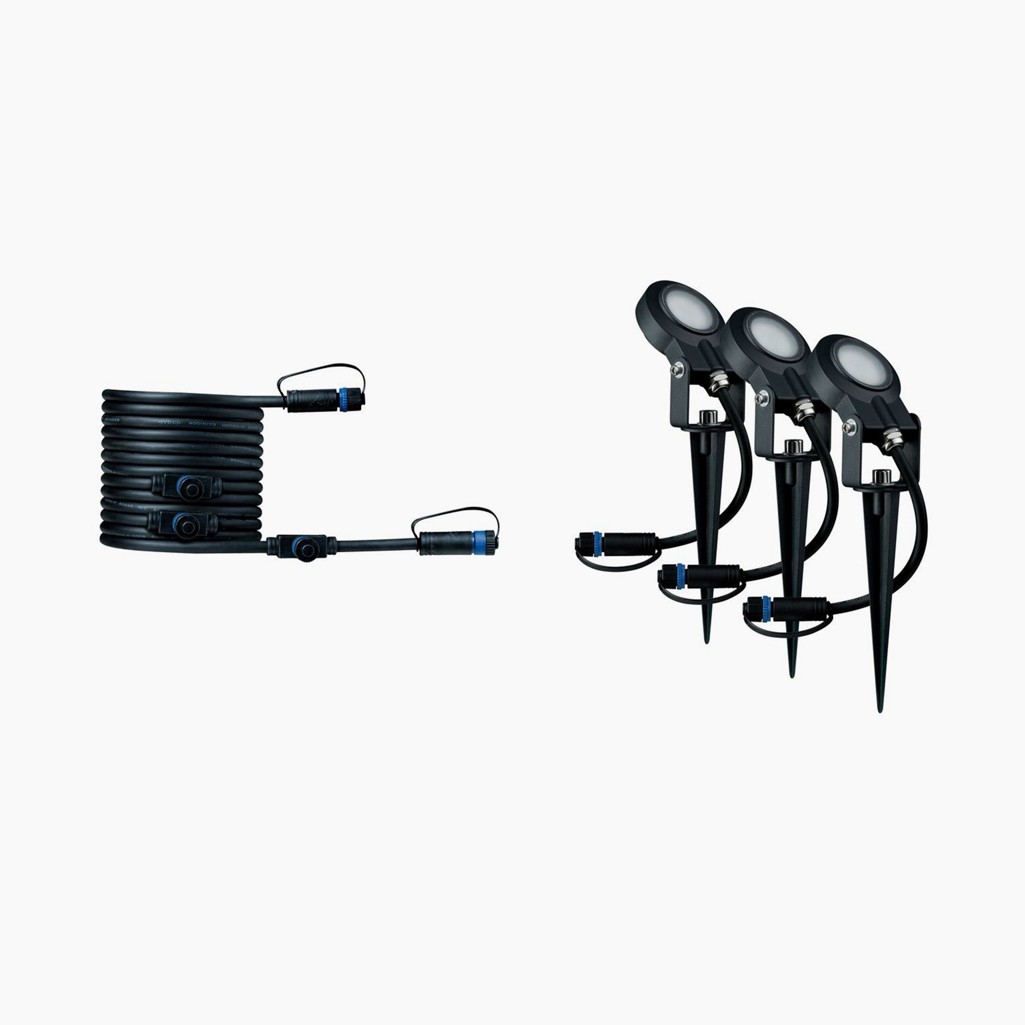 A black coiled wire and three weather-resistant outdoor spotlights with stakes, part of the Paulmann - Plug & Shine Outdoor Sting 18W LED Warm White Expansion Set in Anthracite, are arranged against a white background. These luminaires provide both functionality and durability for any outdoor setting.