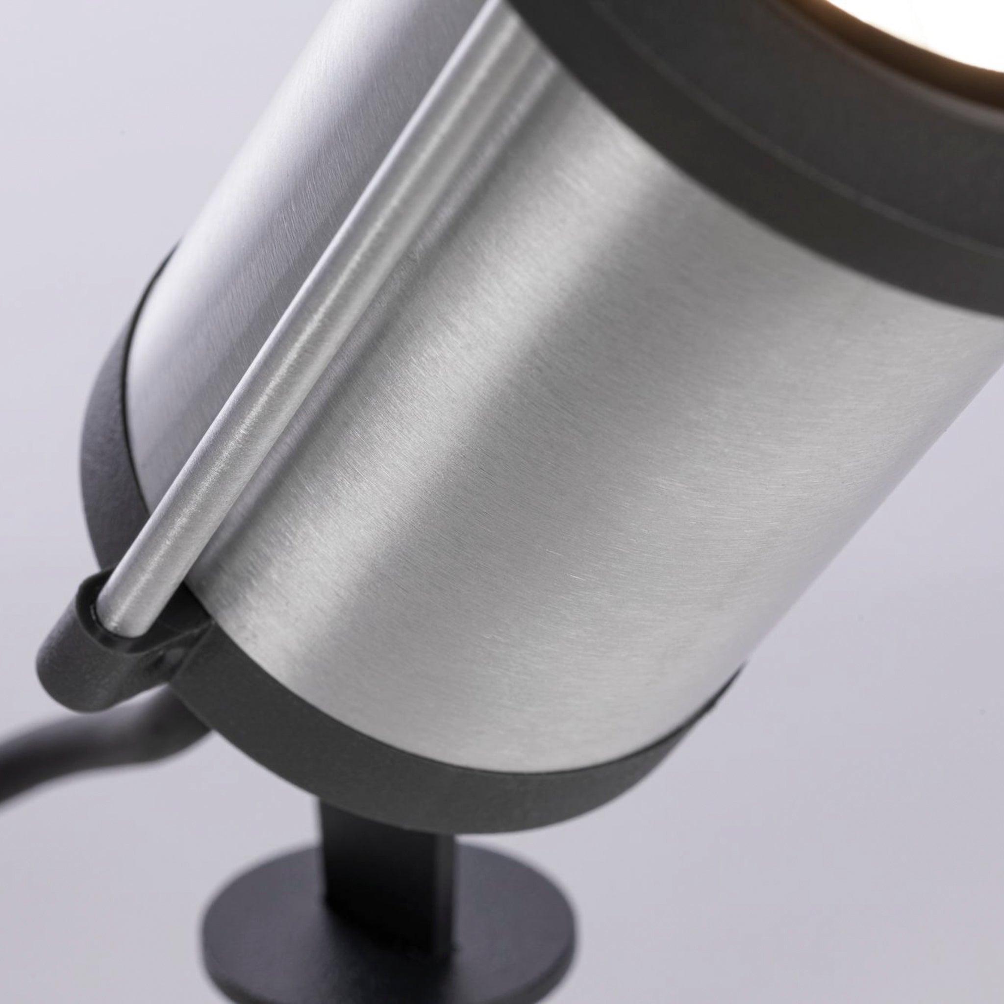 Close-up of the Paulmann - Plug & Shine Outdoor Classic 5.2W LED Individual Spotlight in Anthracite, featuring a cylindrical metal design with a black stand, casting warm white light against a gray background.