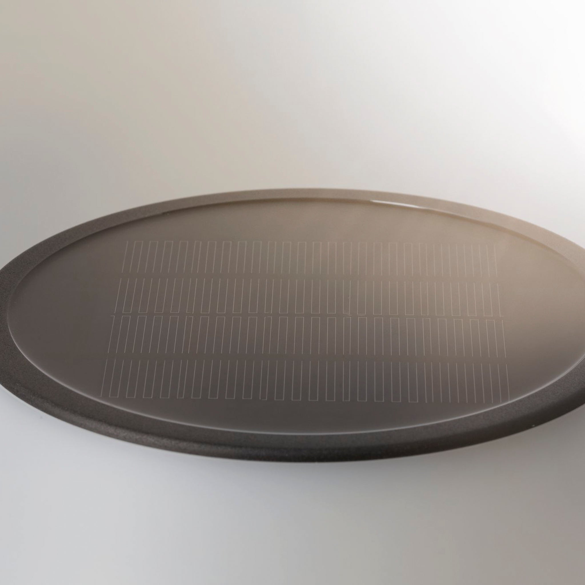 Oval black tray with a grid-patterned glass bottom, elegantly placed on a white surface, perfectly complements your garden lighting when paired with the Outdoor Lillesol 0.8W LED Solar Table Lamp with 3-Step Dim in Stainless Steel.