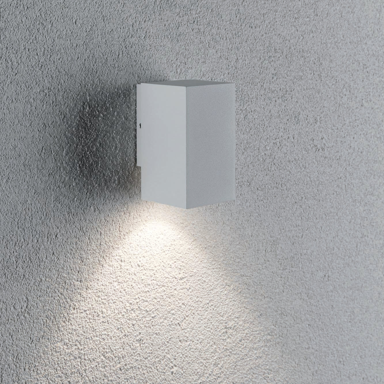 The Outdoor Flame 5.2W LED Single Output Wall Light in White is a minimalist surface-mounted wall luminaire that casts attractive lighting effects with a downward beam on a textured grey surface, utilizing efficient LED technology.