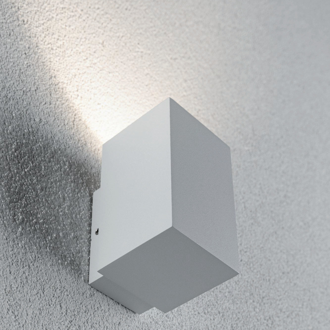 The Outdoor Flame 5.2W LED Single Output Wall Light in White is a minimalist, rectangular, surface-mounted wall luminaire that projects efficient LED technology upwards on a white textured wall, creating attractive lighting effects.