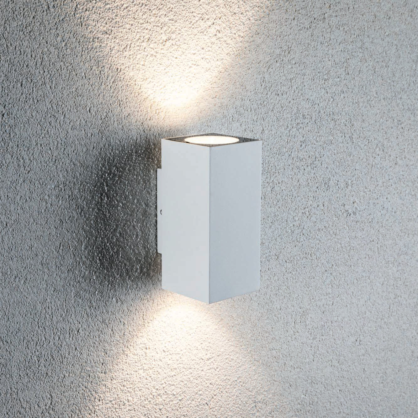 The Outdoor Flame 6.6W LED Dual Output Wall Light in White is a modern wall-mounted luminaire with a rectangular design, emitting light upwards and downwards on a textured wall, and featuring efficient LED technology for attractive lighting effects.