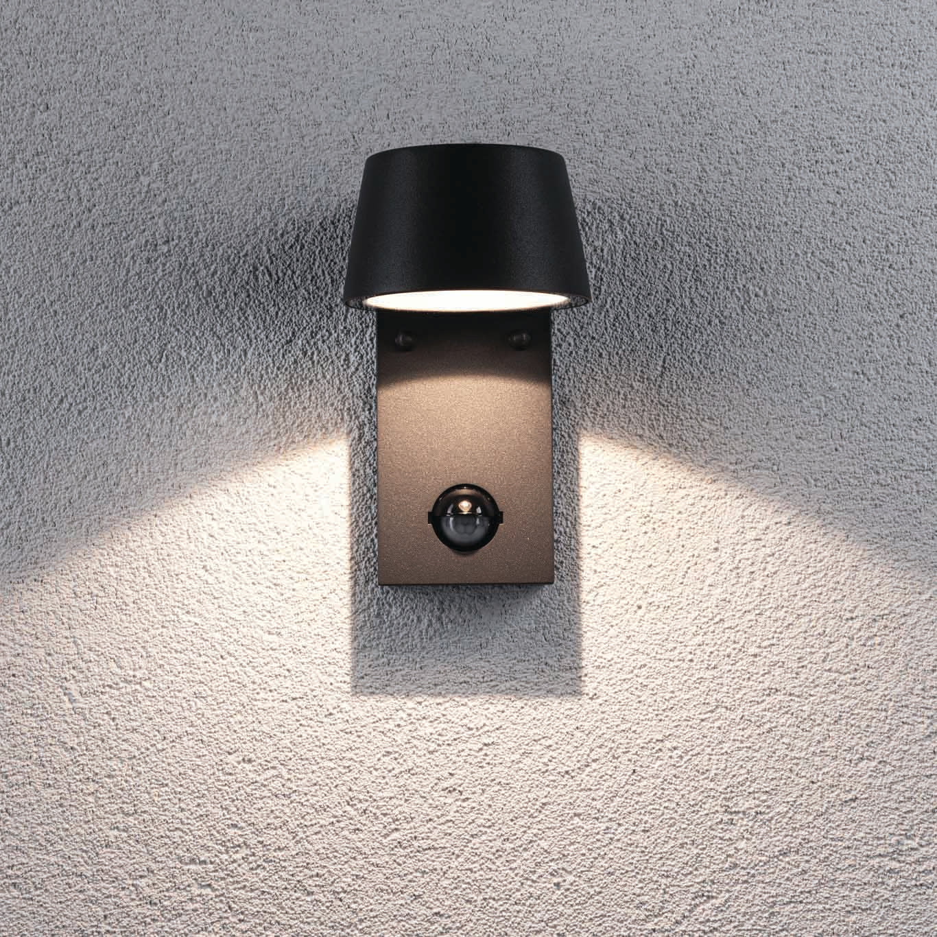 The Paulmann Outdoor Capea 8W LED Wall Light with Motion Detection in Anthracite is a sleek and modern black fixture featuring a cylindrical shade, ideal for outdoor settings. It is mounted on a textured surface and has an IP44 rating, ensuring it withstands the elements.