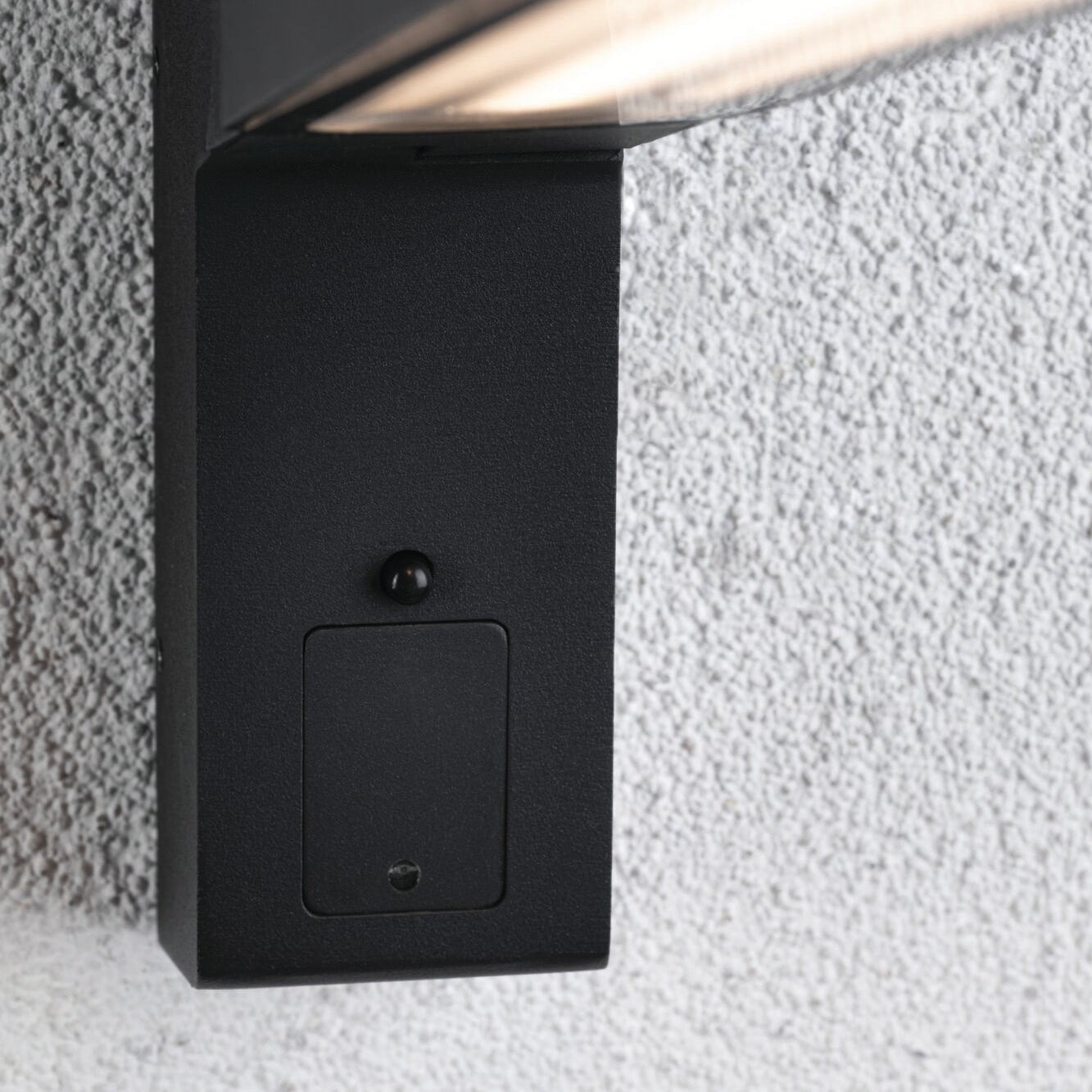 Close-up of a wall-mounted LED outdoor light fixture in anthracite on a textured surface, featuring IP44 splash protection. This sleek Paulmann - Outdoor Ito 7.5W LED Vertical Wall Light with Motion Detection ensures style and durability.