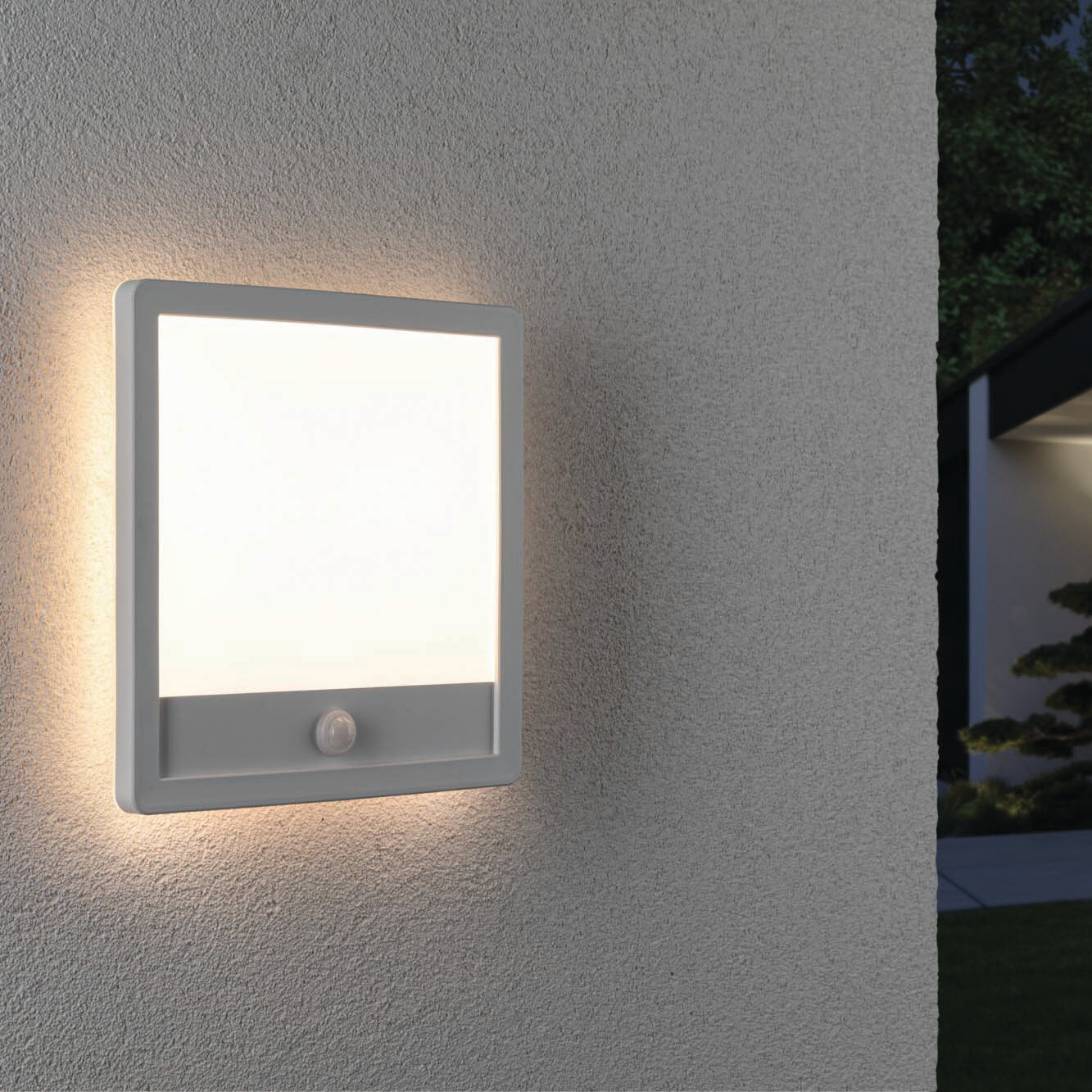 The Paulmann Outdoor Lamina 15.5W LED Backlit Square Wall Light with Motion Detection in White gently illuminates a textured white wall, casting a cozy warm white glow.