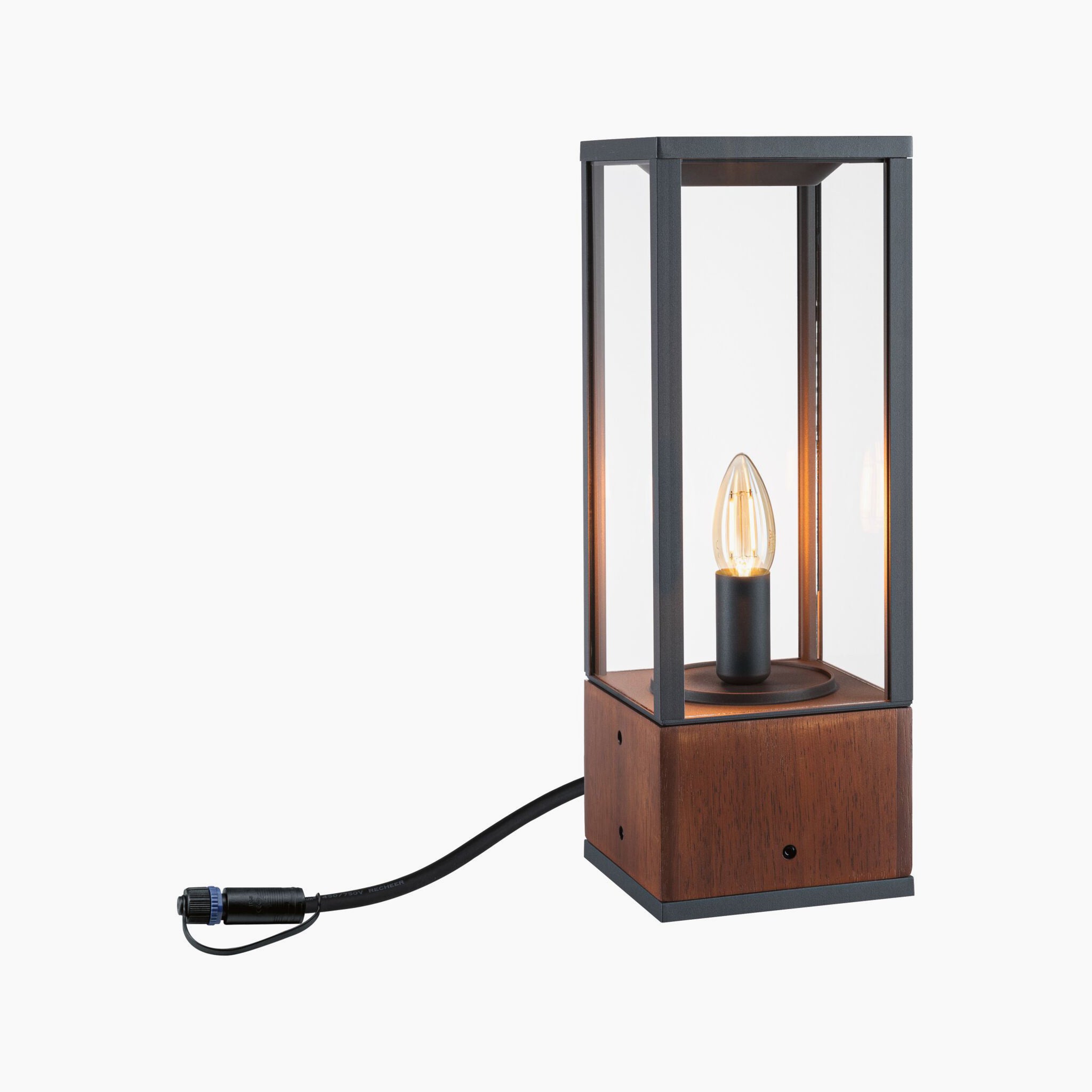 The Paulmann - Plug & Shine Outdoor Vena 2W LED 40cm Wooden Single Bollard Light is a contemporary lighting piece with a wooden base and glass enclosure, showcasing an exposed bulb and power cord, ideal for creating ambient lighting in any environment.