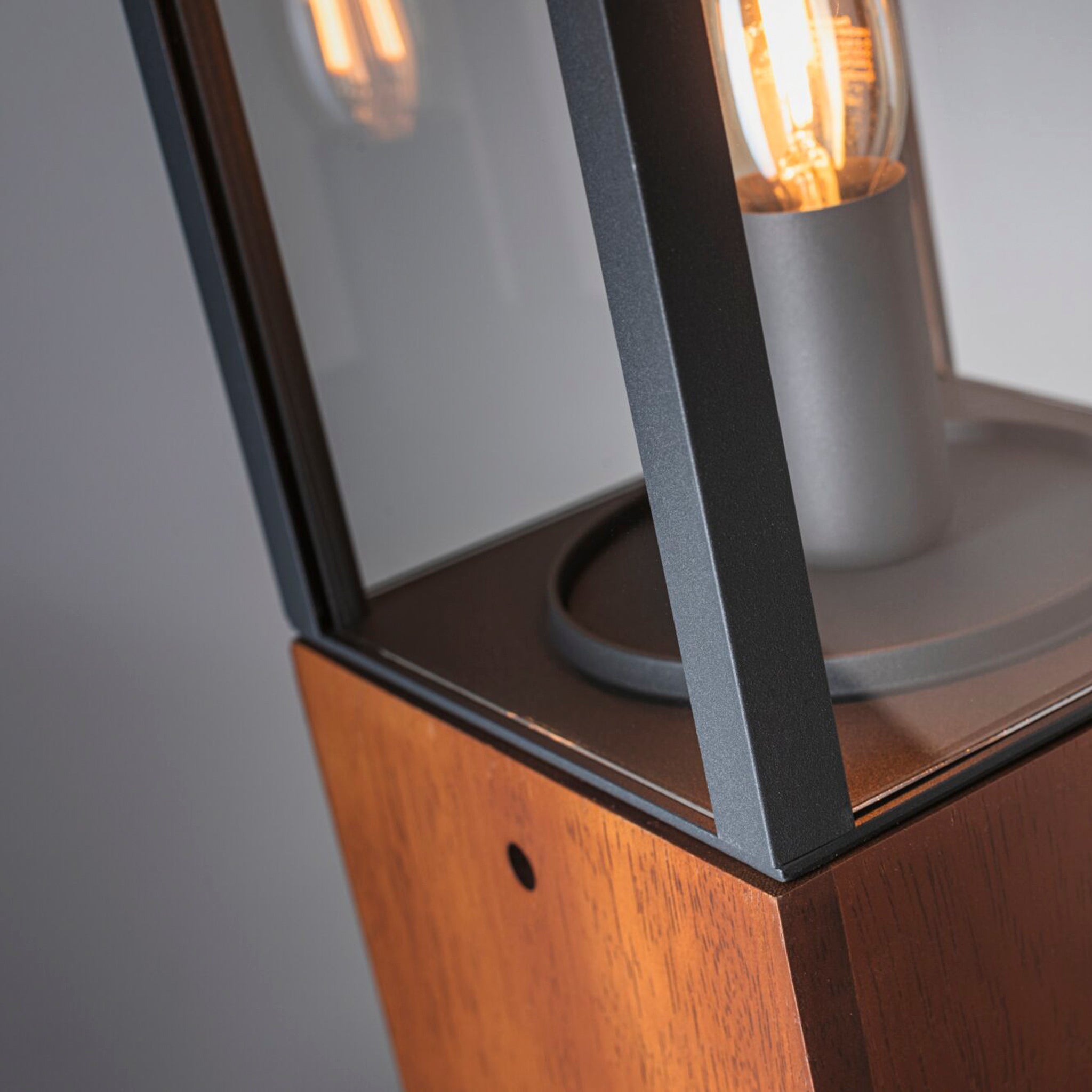 Close-up of the Paulmann Plug & Shine Outdoor Vena Bollard Light: a modern 40cm lamp featuring a wooden base and a visible filament-style LED, encased in a clear glass and metal frame, ideal for creating atmospheric lighting in outdoor spaces.