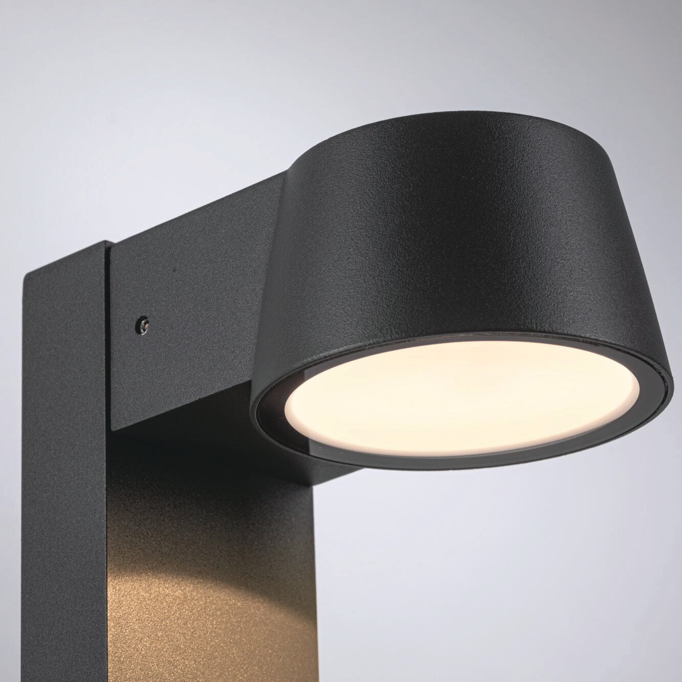 Close-up of the sleek, anthracite-colored Outdoor Capea 8W LED Bollard Light with a wide circular lampshade, emitting gentle, insect-friendly light.