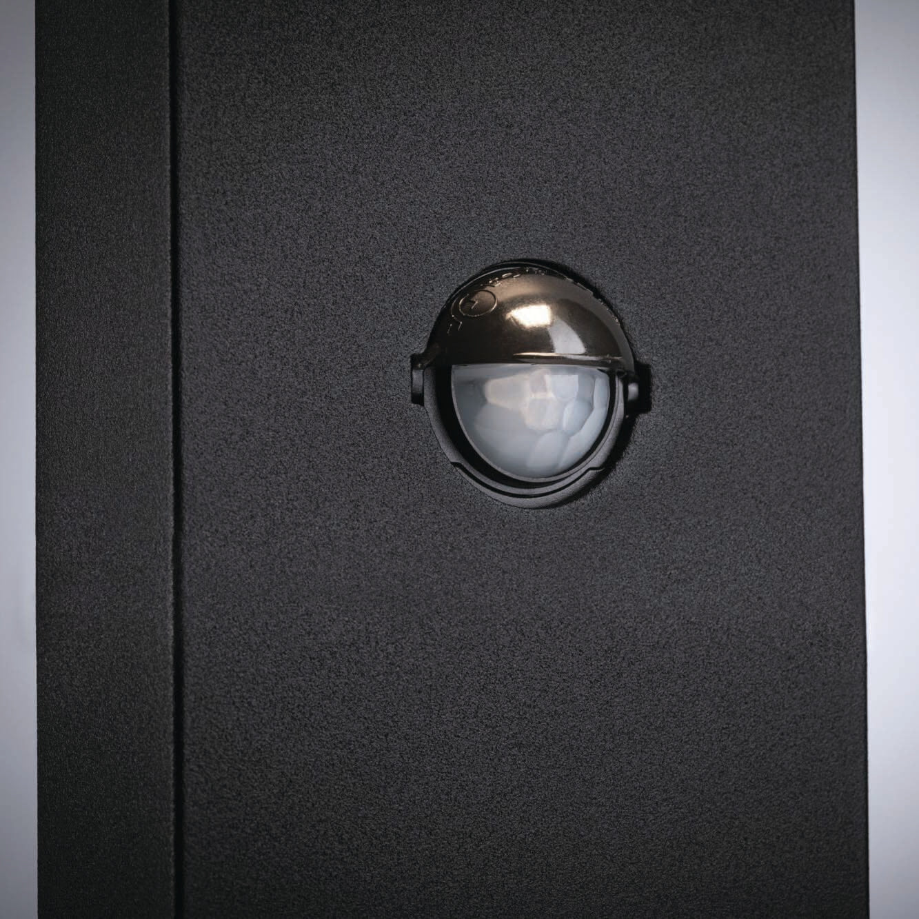 Close-up of the Outdoor Kulma 9W LED Bollard Light with Motion Detection, embedded in a dark gray wall and featuring an anthracite finish that adds a sleek touch to the design.