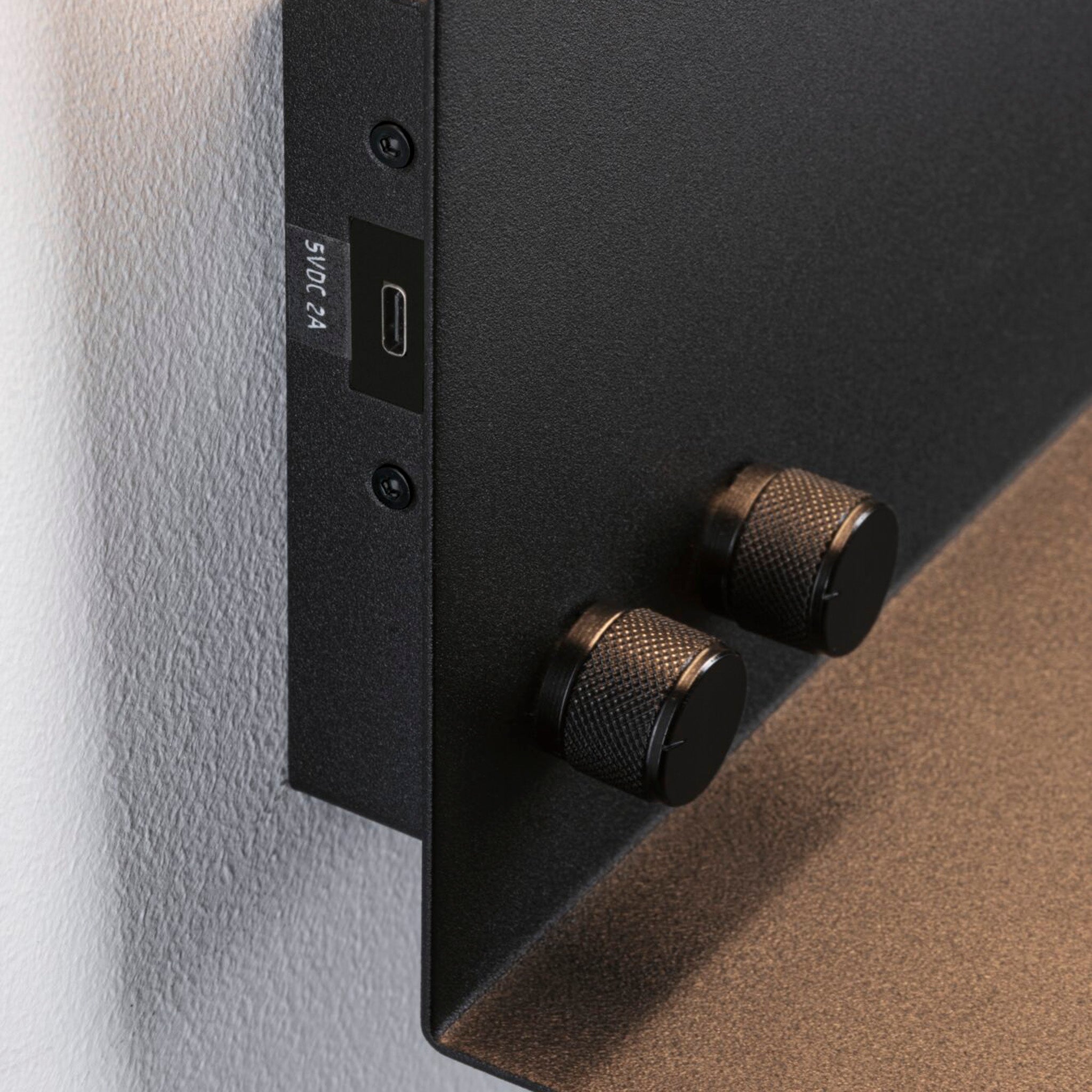 Close-up of the Paulmann Jarina 7.5W LED dimmable wall light in black matt, showcasing a USB-C charging port and two knurled knobs on the side for a stylish yet functional design.