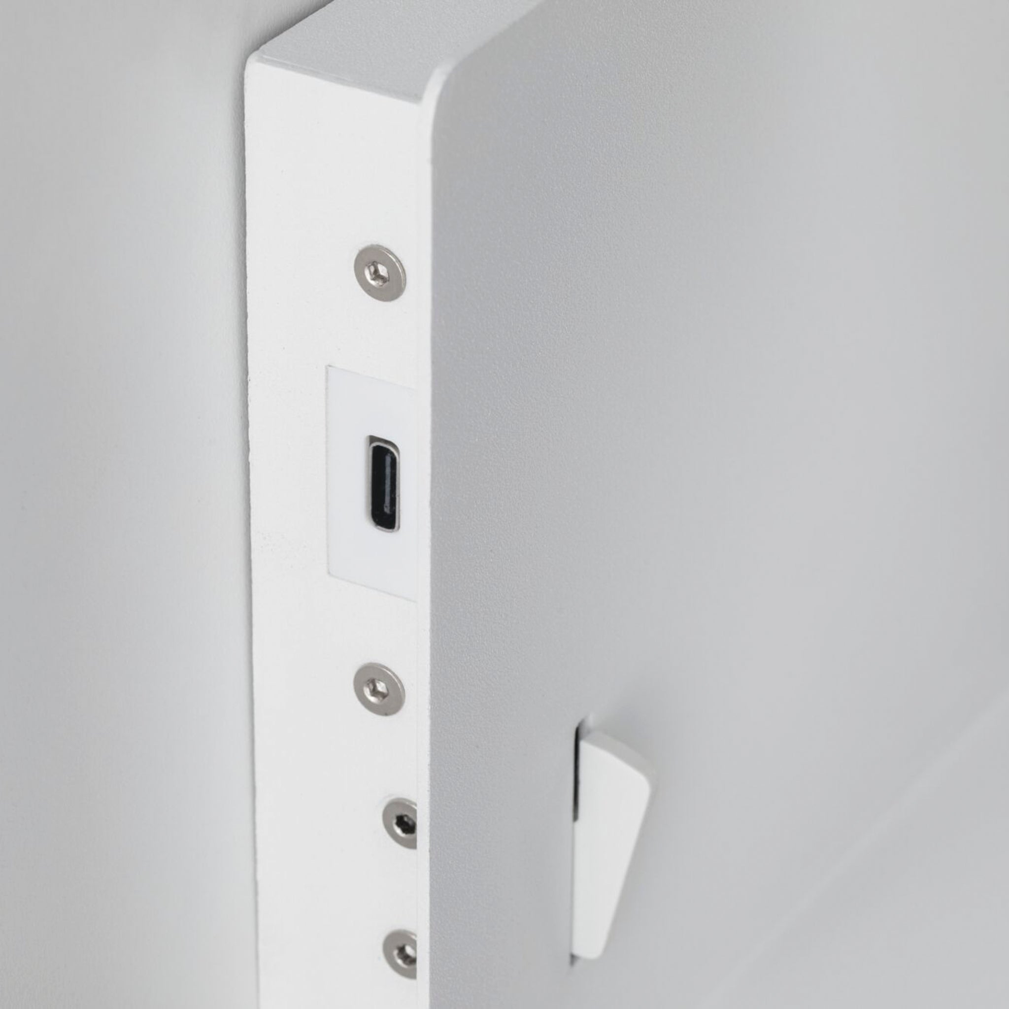 A close-up of the white matte finish on the Devara 40W Wall Mounted Lamp reveals a small USB-C charging port and several screw holes along the edge, making it ideal for use as a wall-mounted reading luminaire with an integrated shelf.