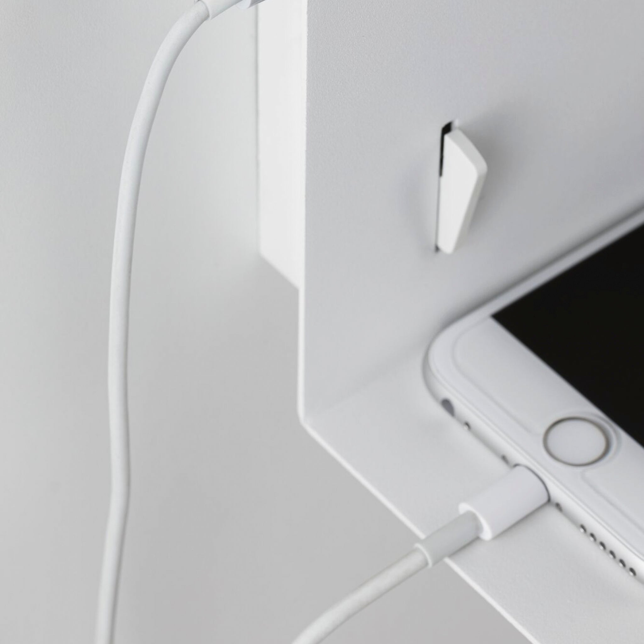 Smartphone charging on the white, integrated shelf of the Devara 40W Wall Mounted Lamp with USB Port in White Matt, right next to a wall-mounted hook.