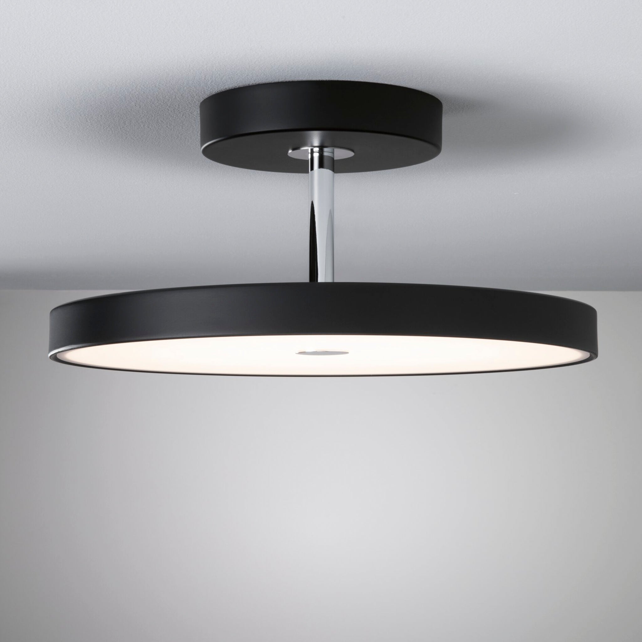 The Paulmann - Hildor 30W LED 2100lm Ceiling Light in Black Matt/Chrome, showcasing a modern design, gracefully illuminates the white ceiling with its dimmable 3-step LED technology.