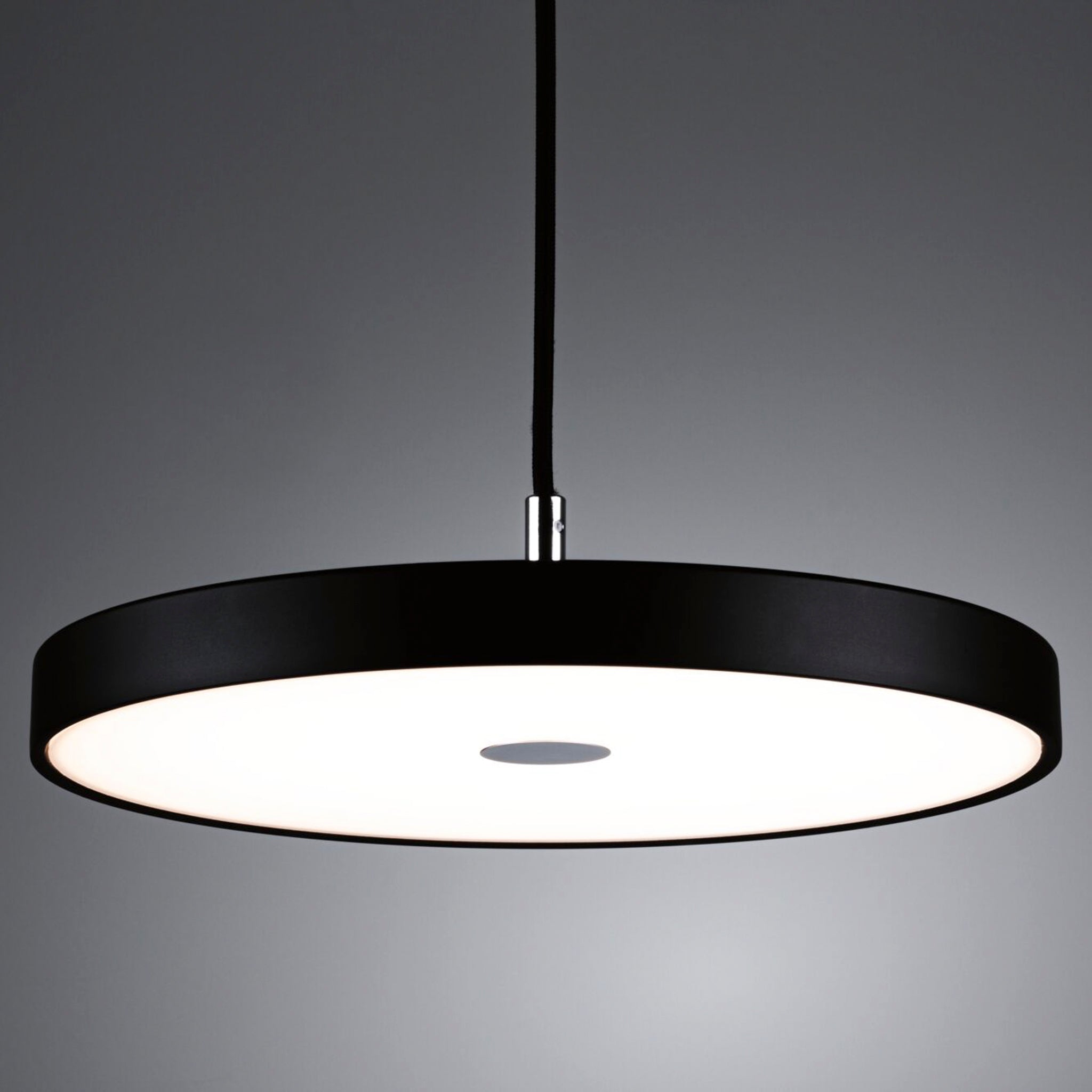 The Paulmann - Hildor 25W LED 1600lm Pendant Light with 3-Step Dim in Black Matt showcases a sophisticated circular design, utilizing advanced LED technology to produce a striking contrast with its illuminated white center against a grey backdrop.