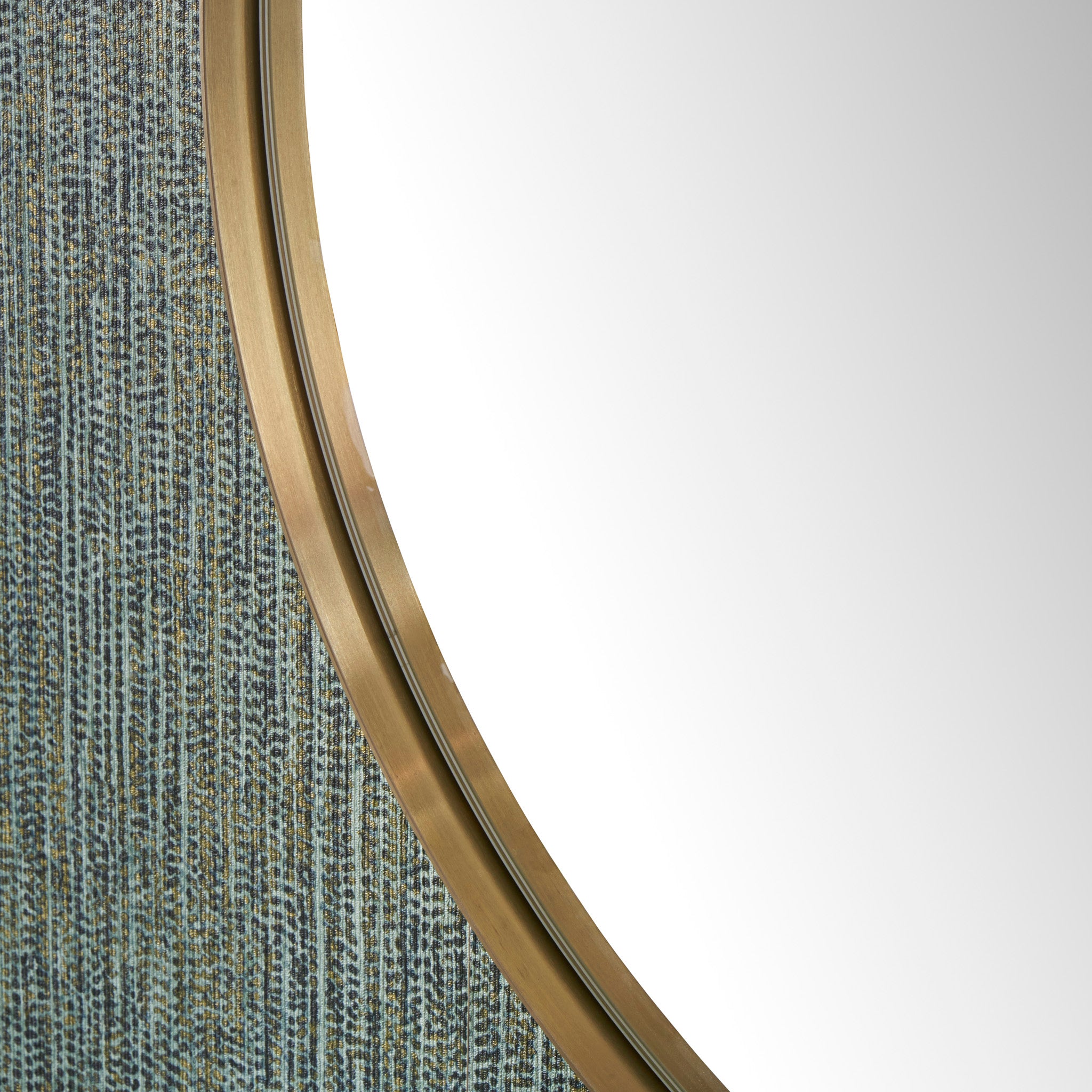 Close-up of the Brushed Gold Metal Slim Frame Round Wall Mirror Large set against a textured, blue-gray patterned background.