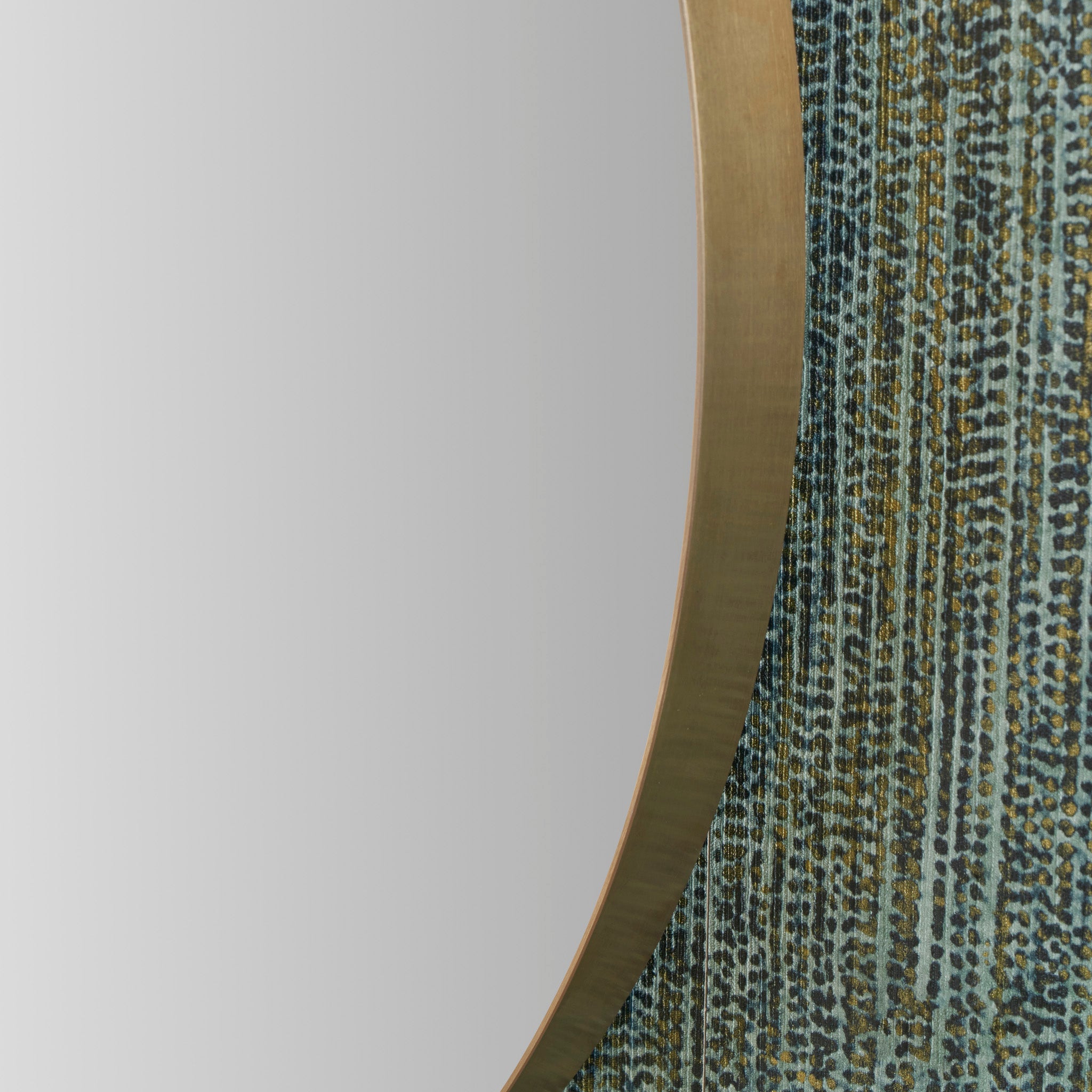 Close-up of the Brushed Gold Metal Slim Frame Round Wall Mirror Medium, featuring a textured, patterned surface against a light gray background.