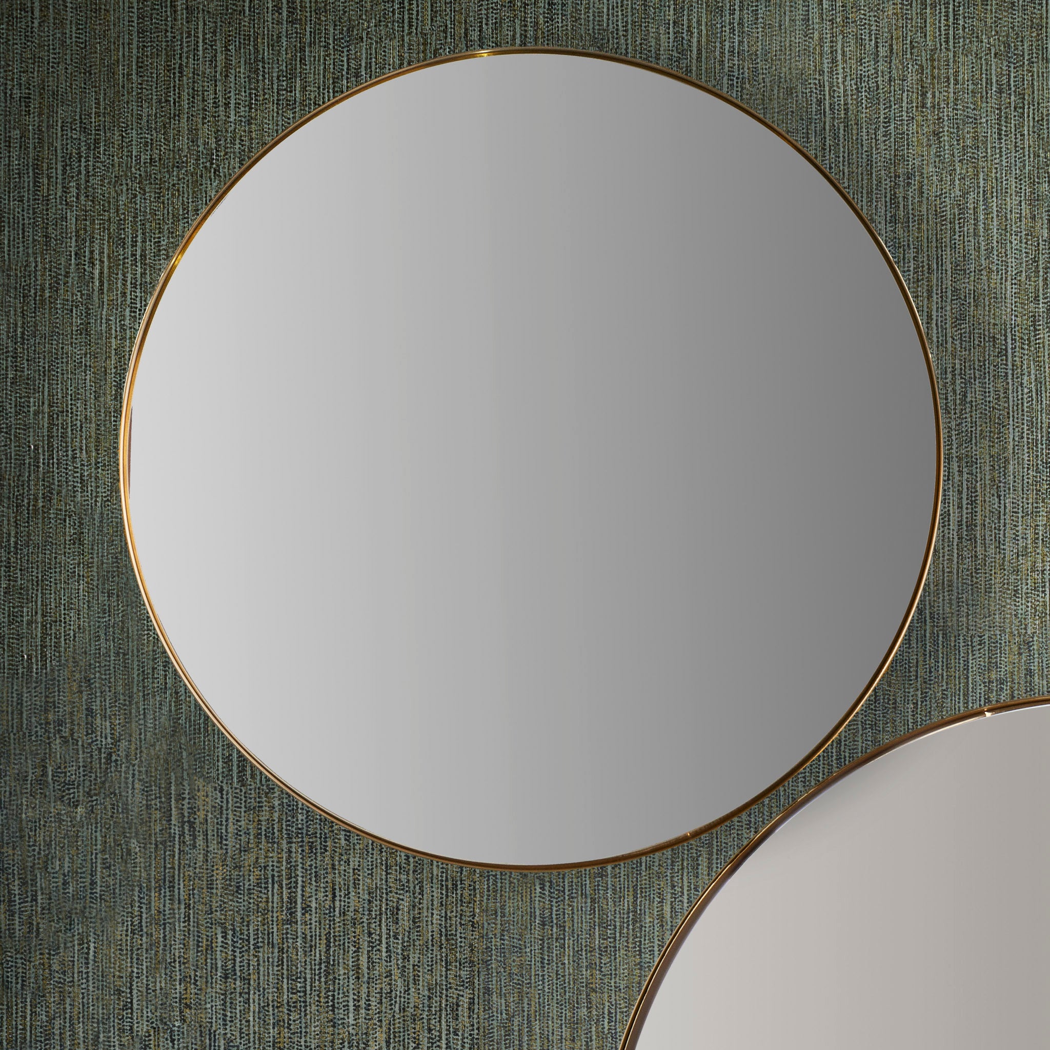 A pair of Brushed Gold Metal Slim Frame Round Wall Mirrors Medium are displayed on a textured green wall.