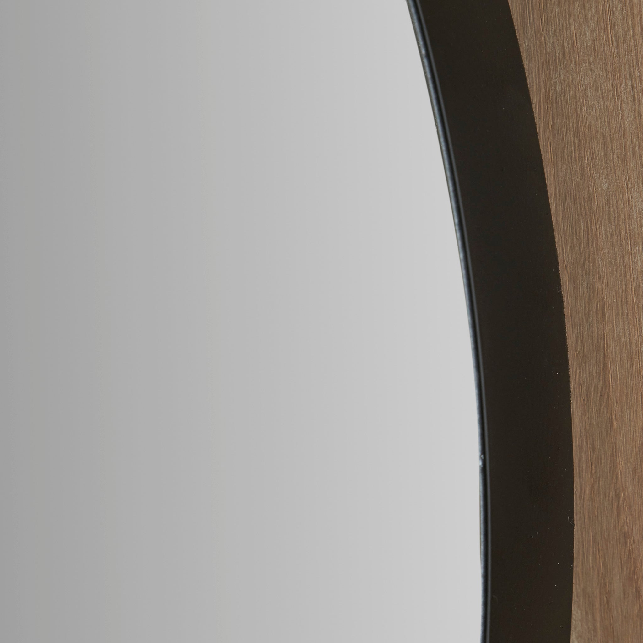 Close-up of the Black Metal Slim Frame Round Wall Mirror Large, showcasing its sleek metal frame and a partial view of the reflective surface.