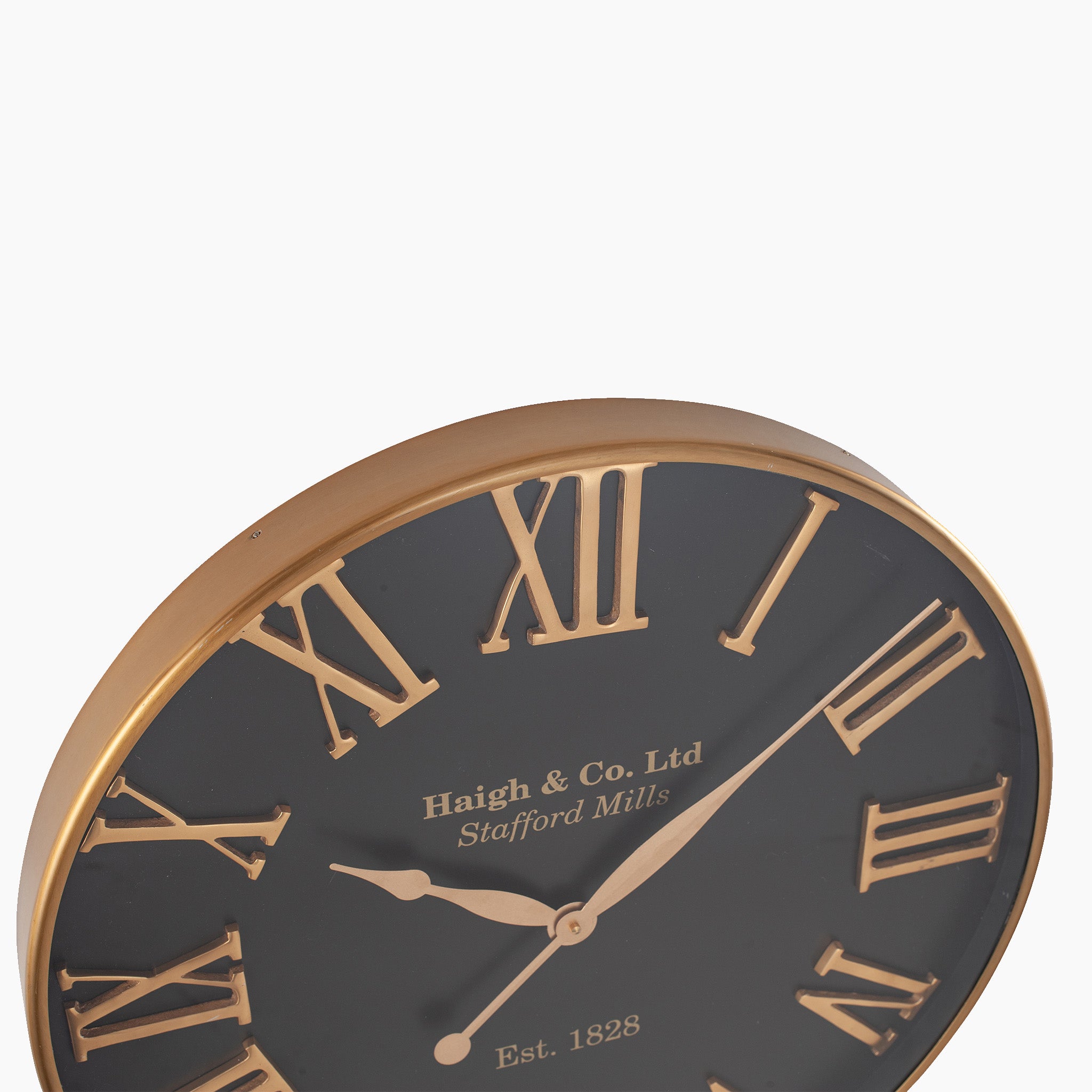 The Antique Gold and Black Metal Wall Clock showcases oversized Roman numerals against a sleek black face, elegantly displaying "Haigh & Co. Ltd Stafford Mills," making it an ideal centerpiece for contemporary interiors.