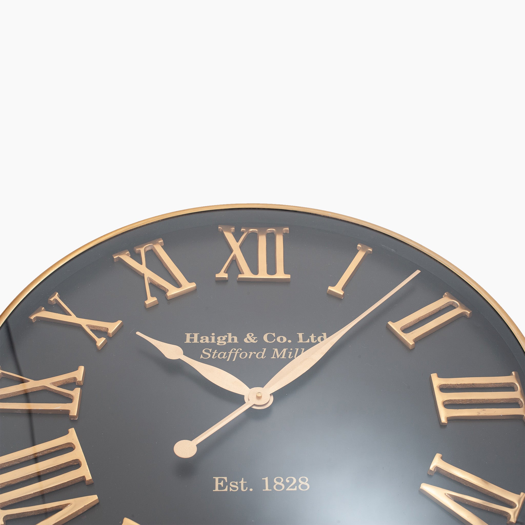 A close-up of the Antique Gold and Black Metal Wall Clock featuring oversized Roman numerals, adorned with the text "Haigh & Co. Ltd, Stafford Mills, Est. 1828," effortlessly combining timeless elegance with modern interiors.