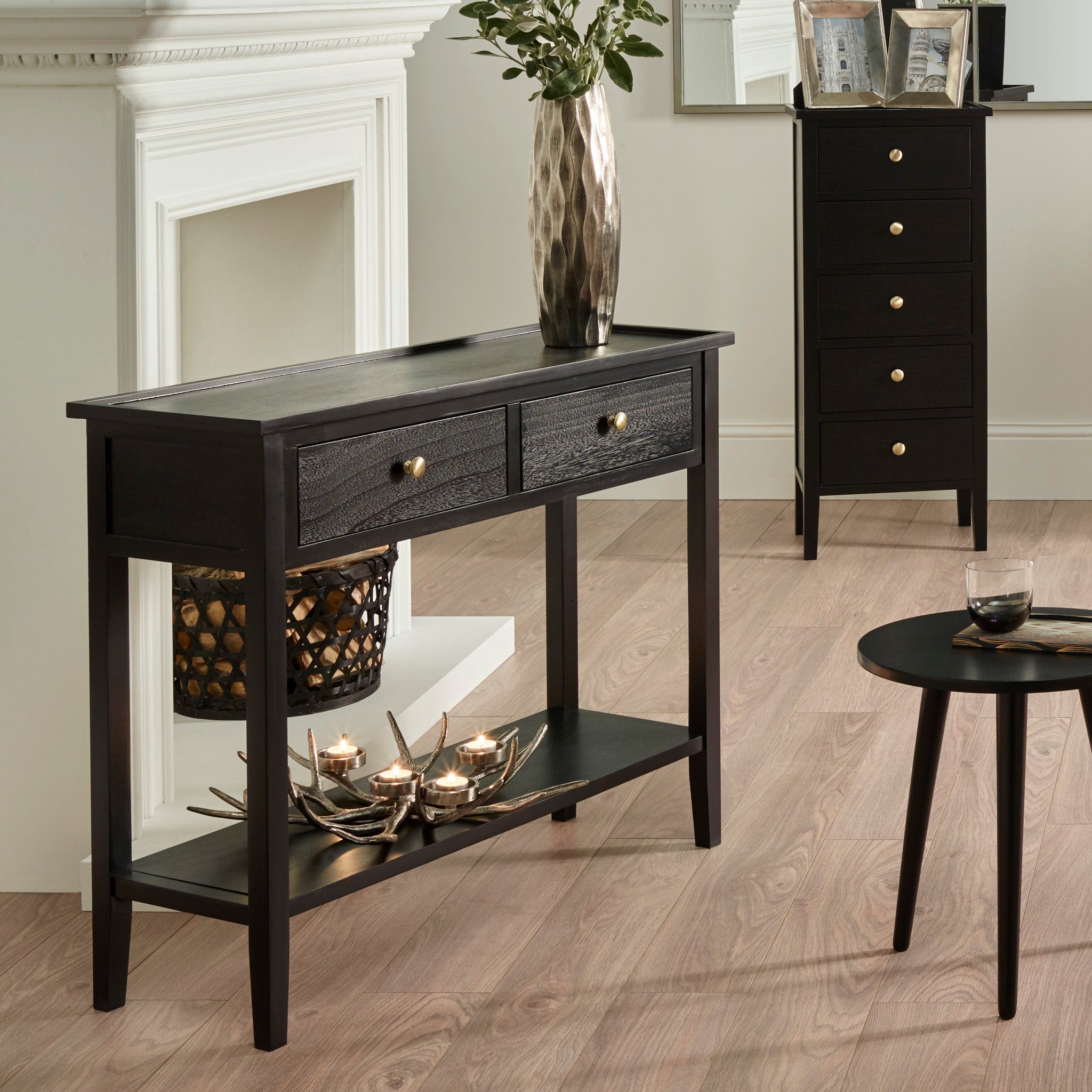 The Fairford Satin Black Pine Wood 2 Drawer Console Table, adorned with a vase and decorative items, enhances the stylish mid-century aesthetic of the living room.