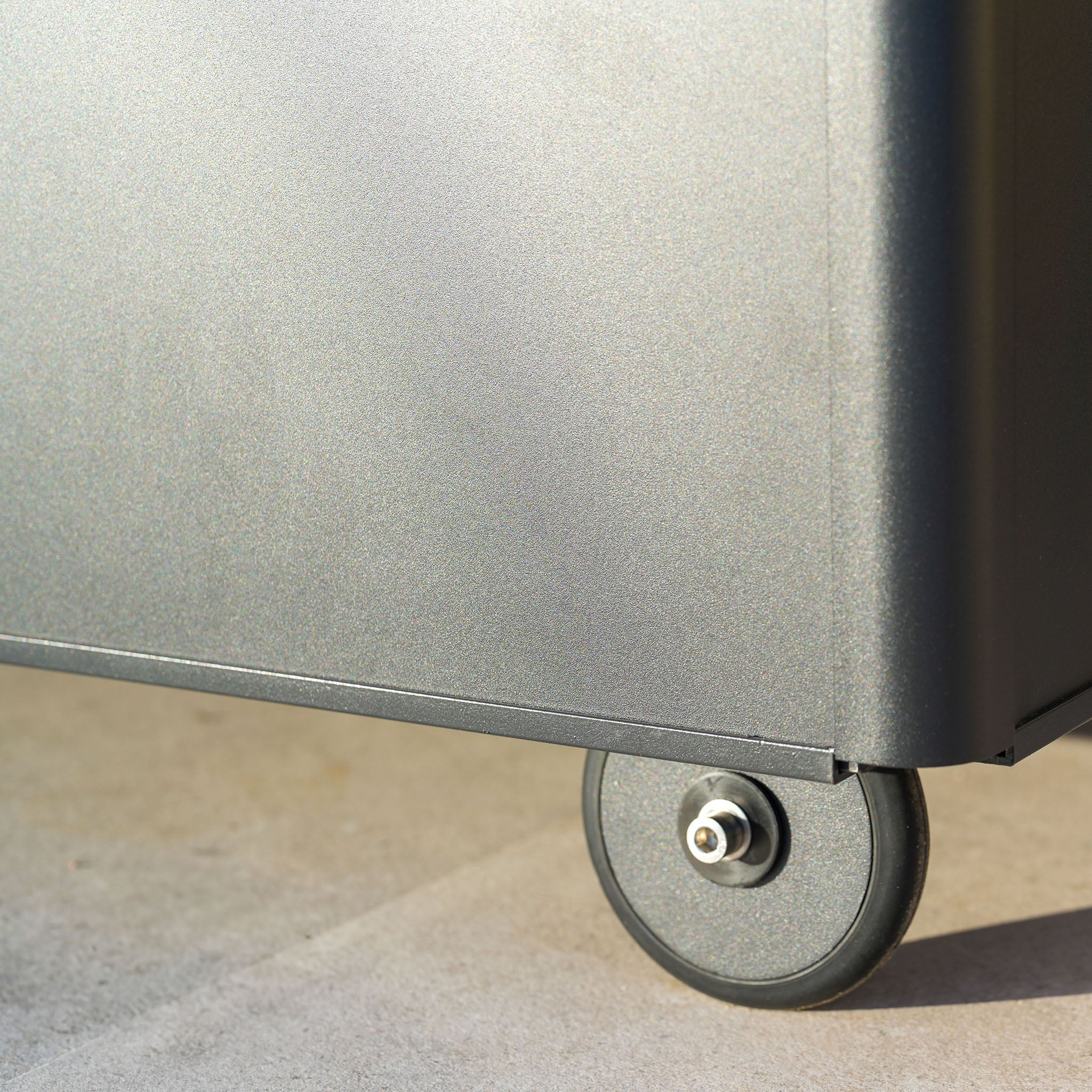 Close-up of the Large Aluminium Storage Box in Grey, featuring aluminium construction on wheeled casters, resting on a light-colored surface.