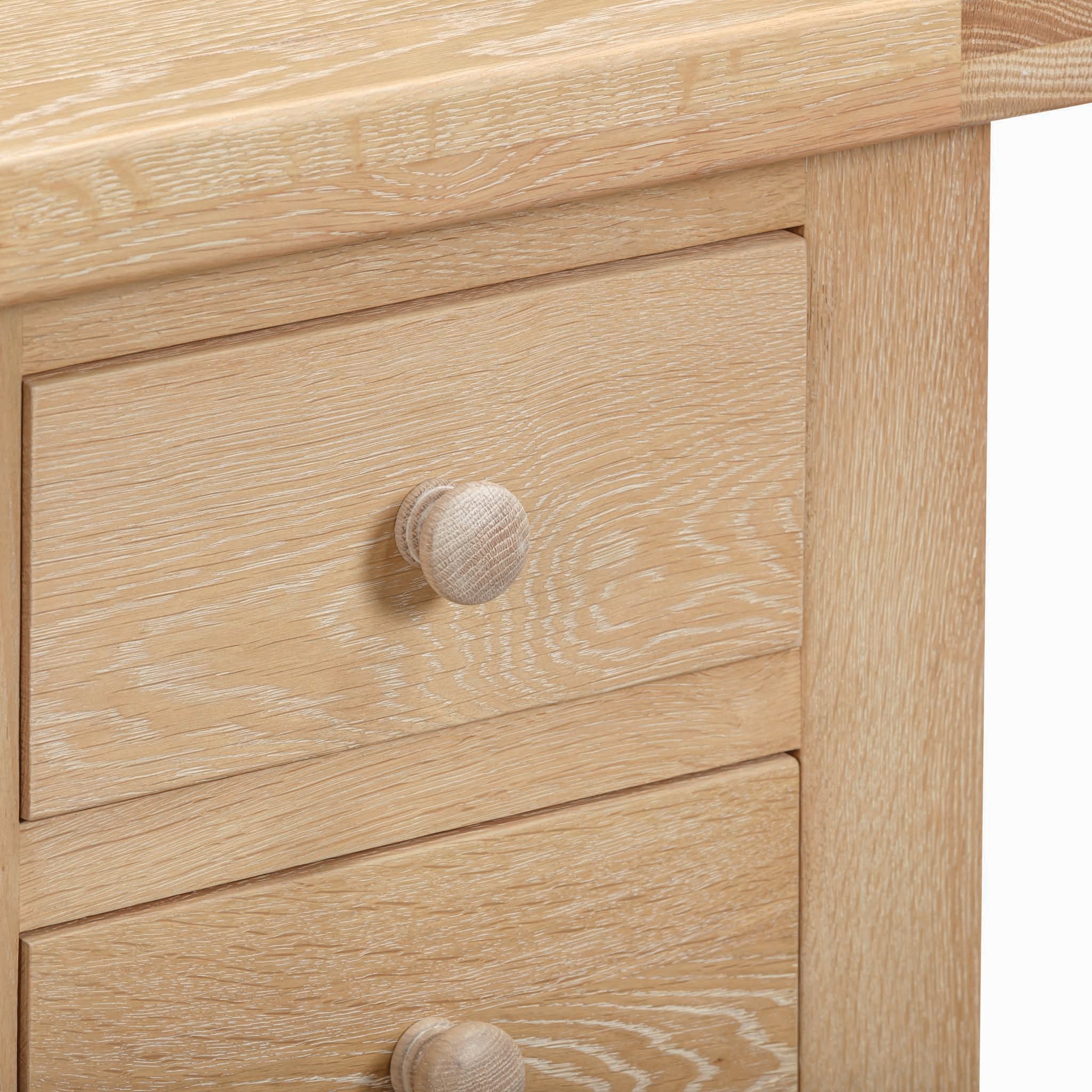 Close-up of the Burford 3 Drawers Bedside Table in Natural Oak, featuring a whitewash finish and three spacious drawers, each adorned with round wooden knobs for ample storage.